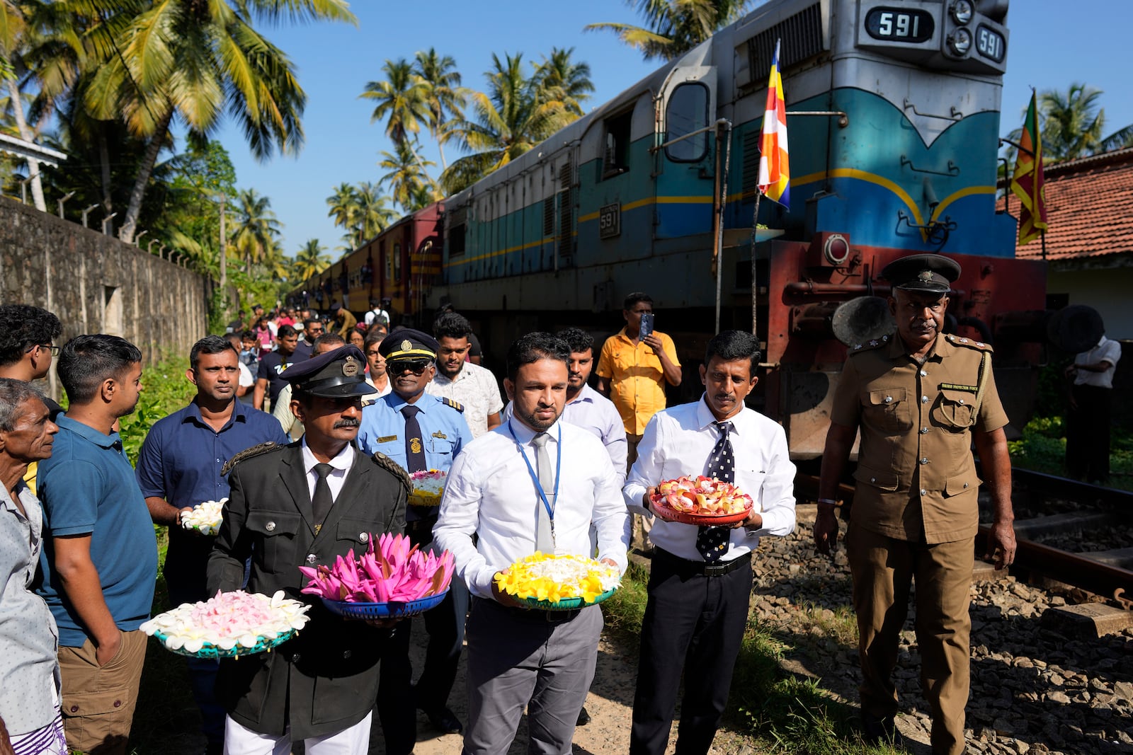 Railway workers and locomotive drivers carry flowers to offer at a memorial built in memory of those who died during 2004 Indian Ocean tsunami as they mark the 20th anniversary in Peraliya, Sri Lanka, Thursday, Dec. 26, 2024. (AP Photo/Eranga Jayawardena)