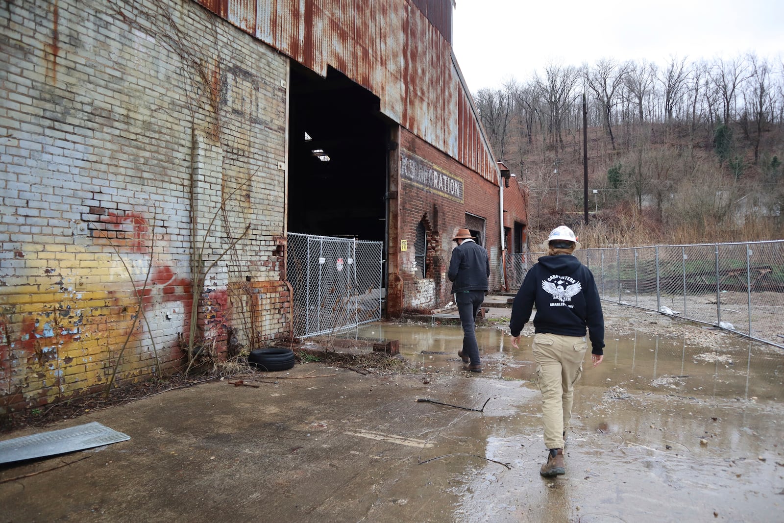 Coalfield Development CEO Jacob Hannah and Assistant Crew Chief Ashley Cain walk toward the gate of the organization’s empty Black Diamond factory construction project in Huntington, W.Va. on Thursday, Feb. 6, 2025. (AP Photo/Leah Willingham)