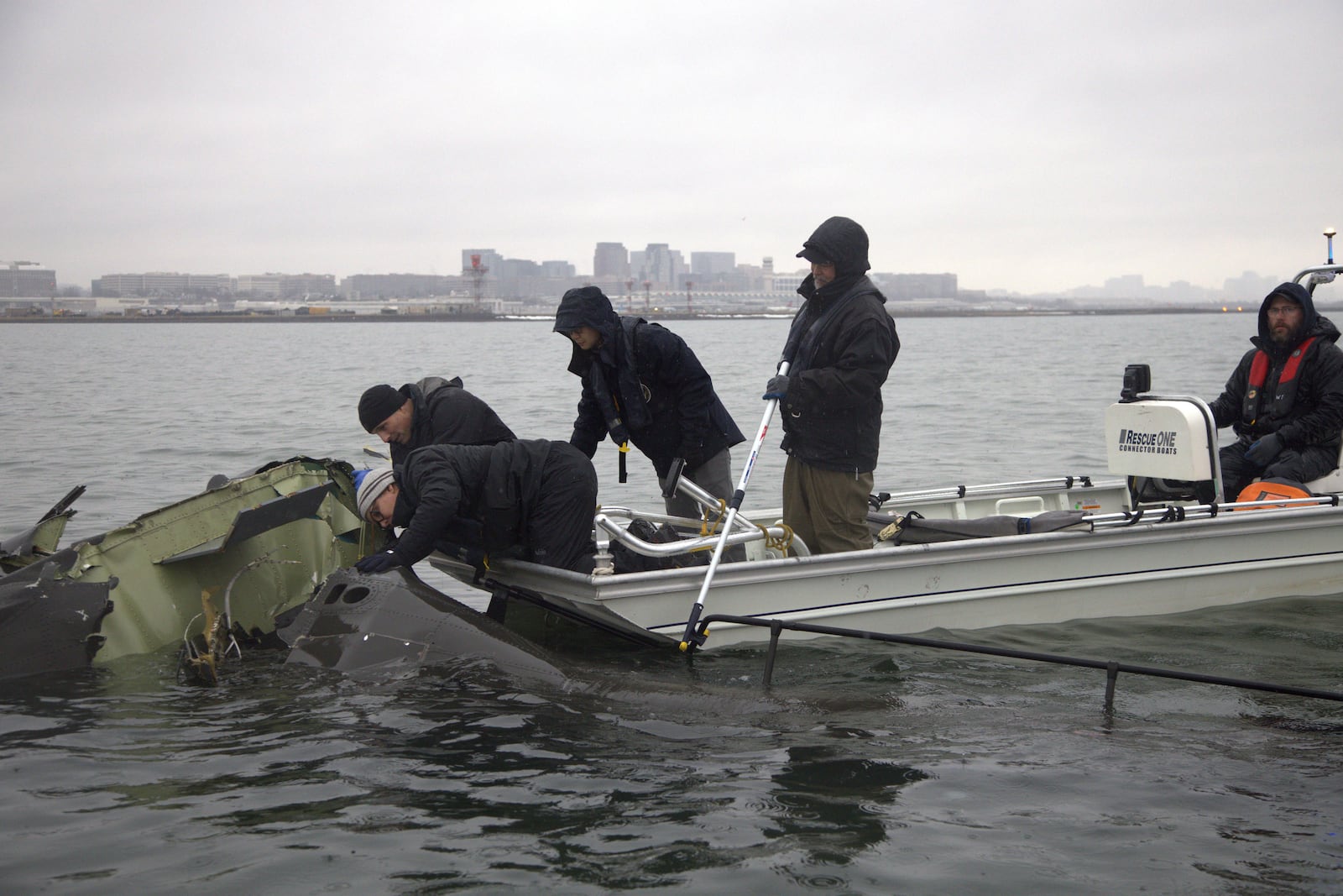 In this undated image provided by the National Transportation Safety Board, NTSB investigators and members of the salvage crew recover wreckage from the Army Black Hawk helicopter that collided with an American Airlines jet Wednesday night, Jan. 29, 2025, near Ronald Reagan Washington National Airport in Arlington, Va. (NTSB via AP)