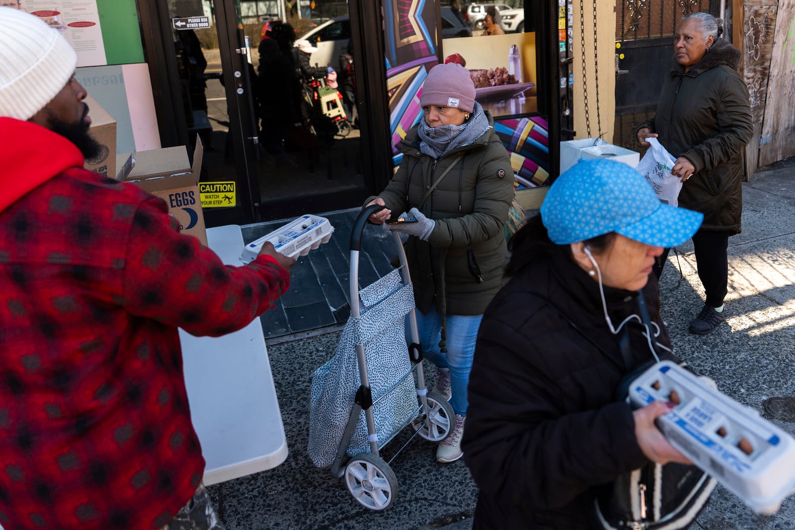 Abou Sow hands out cartons of eggs to people waiting in line to receive free eggs from FarmerJawn Agriculture, Friday, March 21, 2025, in the Harlem neighborhood of New York. (AP Photo/Julia Demaree Nikhinson)