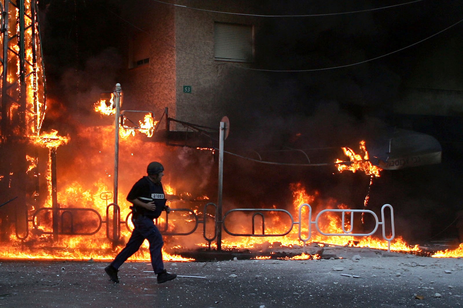 FILE - An Israeli police officer runs to the site where a Hezbollah-fired rocket directly hit a building in the northern costal town of Nahariya, on July 13, 2006. (AP Photo/Ariel Schalit, File)