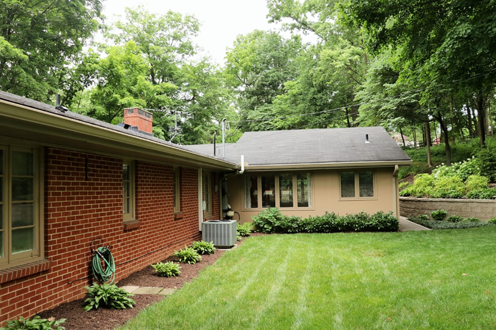 An addition to the original floor plan, the family room has a brick, wood-burning fireplace with raised hearth and brick mantel. A picture window looks out over the terrace garden, and a back door opens to a brick walkway that connects the two rear courtyard settings. CONTRIBUTED PHOTO BY KATHY TYLER