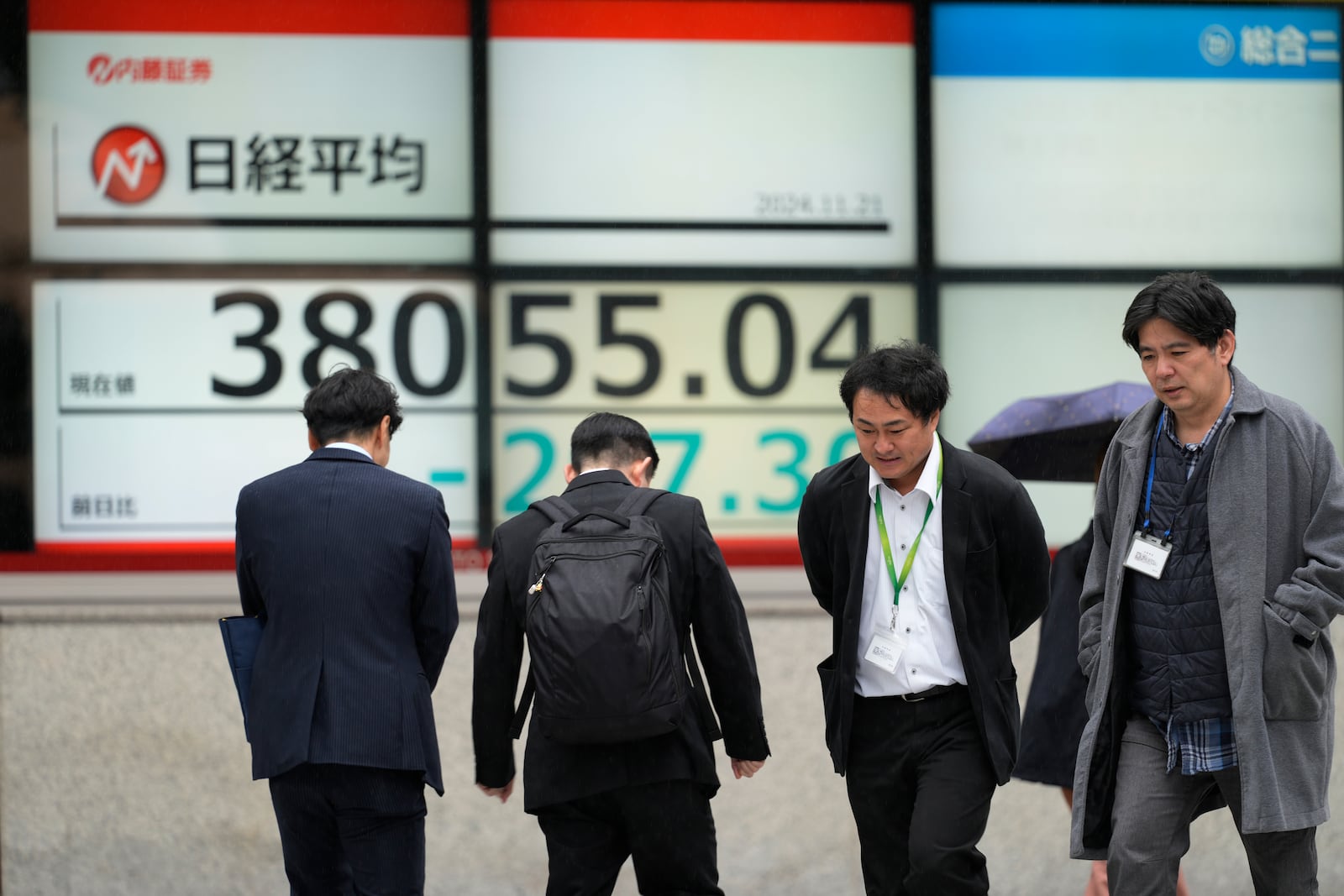 People walk by monitors showing Japan's Nikkei 225 index at a securities firm in Tokyo, Thursday, Nov. 21, 2024. (AP Photo/Hiro Komae)