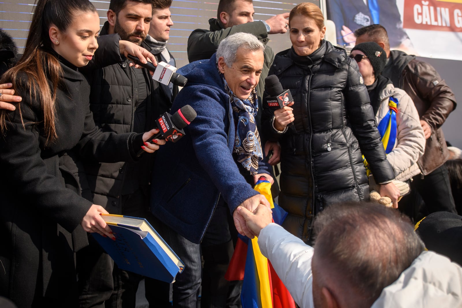 Calin Georgescu, the winner of Romania's first round of presidential election, annulled by the Constitutional Court, shakes hands with one of the thousands of supporters gathered for a protest outside the Romanian parliament in Bucharest, Romania, Saturday, Feb. 22, 2025. (AP Photo/Alexandru Dobre)