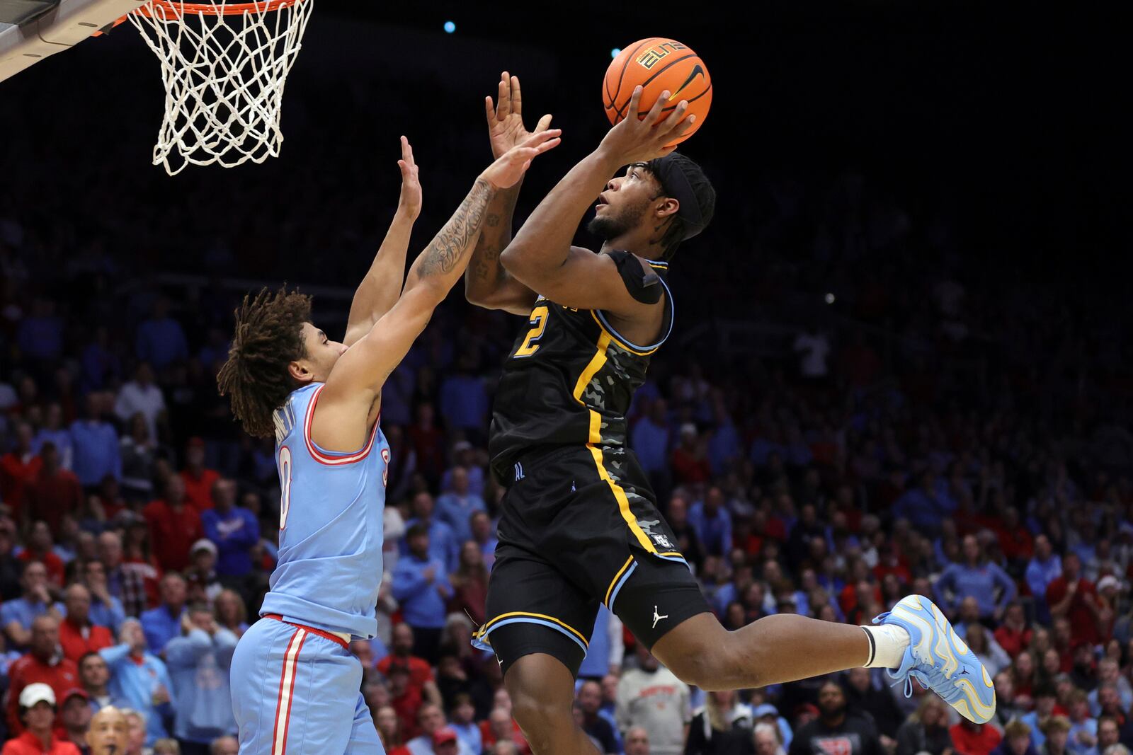 Marquette guard Chase Ross, right, goes up to shoot in front of Dayton guard Javon Bennett, left, during the first half of an NCAA college basketball game in Dayton, Ohio, Saturday, Dec. 14, 2024. (AP Photo/Paul Vernon)