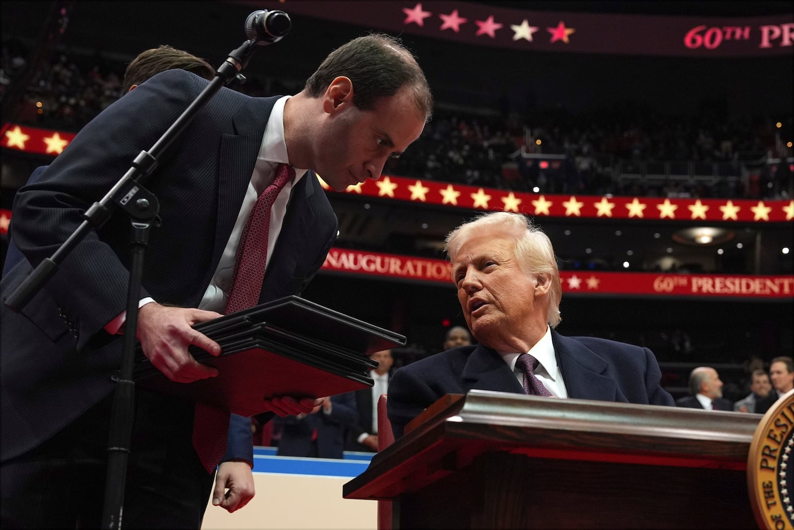 President Donald Trump signs an executive order as he attends an indoor Presidential Inauguration parade event at Capital One Arena, Monday, Jan. 20, 2025, in Washington. (AP Photo/Evan Vucci)