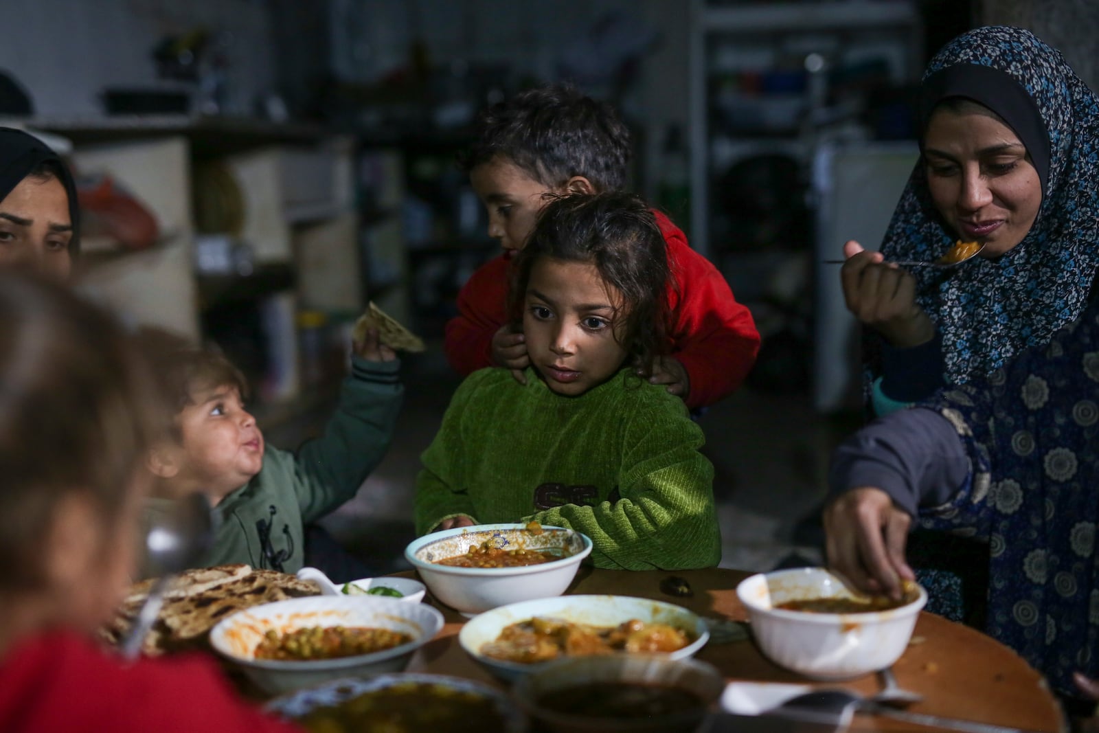 The family of Fatima Al-Absi share Iftar, the fast-breaking meal, on the first day of Ramadan in their damaged apartment in Jabaliya, northern Gaza Strip, on Saturday, March 1, 2025. (AP Photo/Jehad Alshrafi)