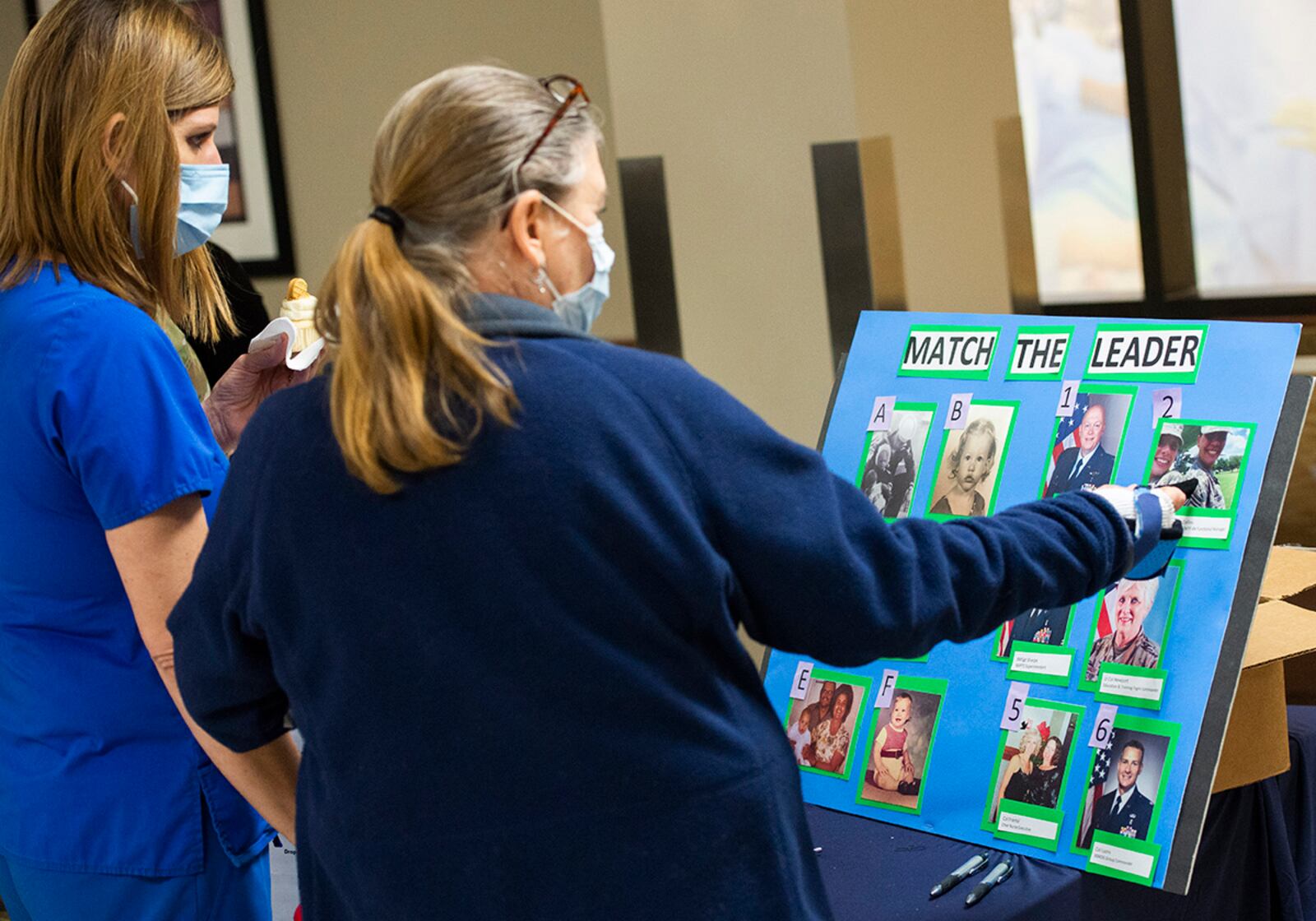 Nurses from the Wright-Patterson Medical Center examine childhood photos that belong to members of the 88th Medical Group leadership team before placing their final guess onto sheets of paper during an event May 12 as part of Nurse and Medical Technician Appreciation Week. U.S. AIR FORCE PHOTO/WESLEY FARNSWORTH