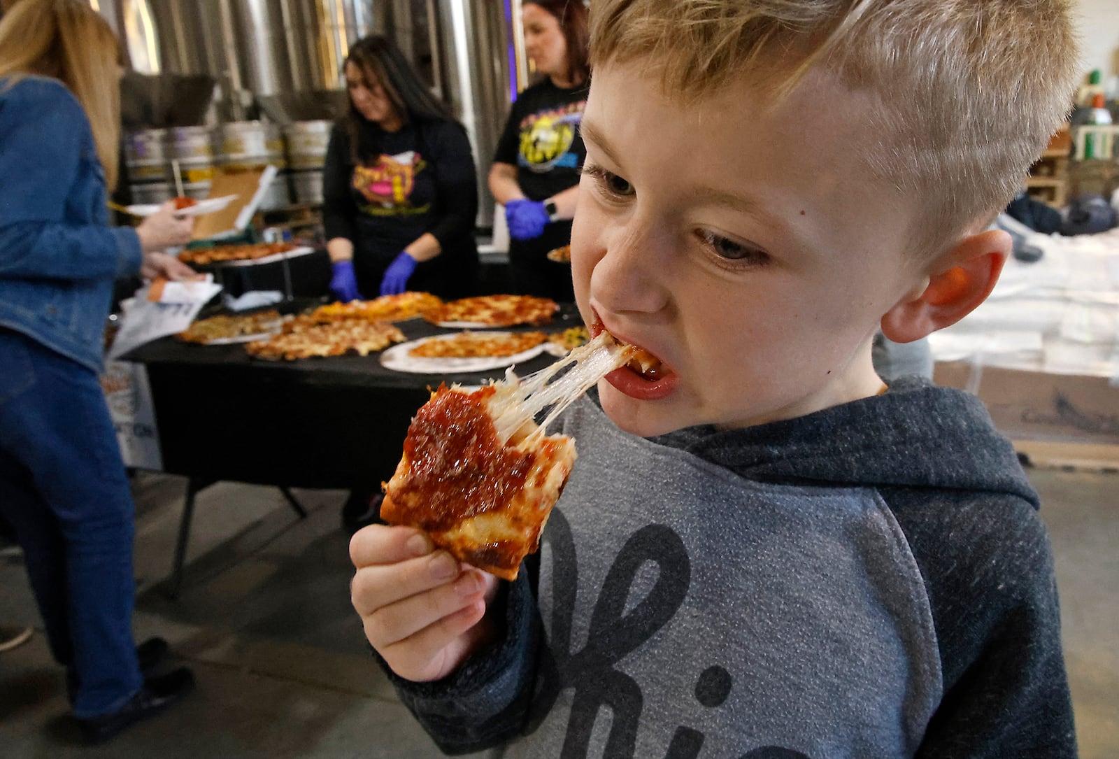 George Conroy enjoys a cheesy piece of pizza at the Slice of Springfield event at Mother Stewarts Brewery Thursday, Feb. 8, 2024. The event offers a chance to taste and vote for the best pizza from eight local pizzerias. The sold out fundraiser was presented by the National Trail Parks and Recreation District and 100% of ticket sales go to support National Trail programs. BILL LACKEY/STAFF