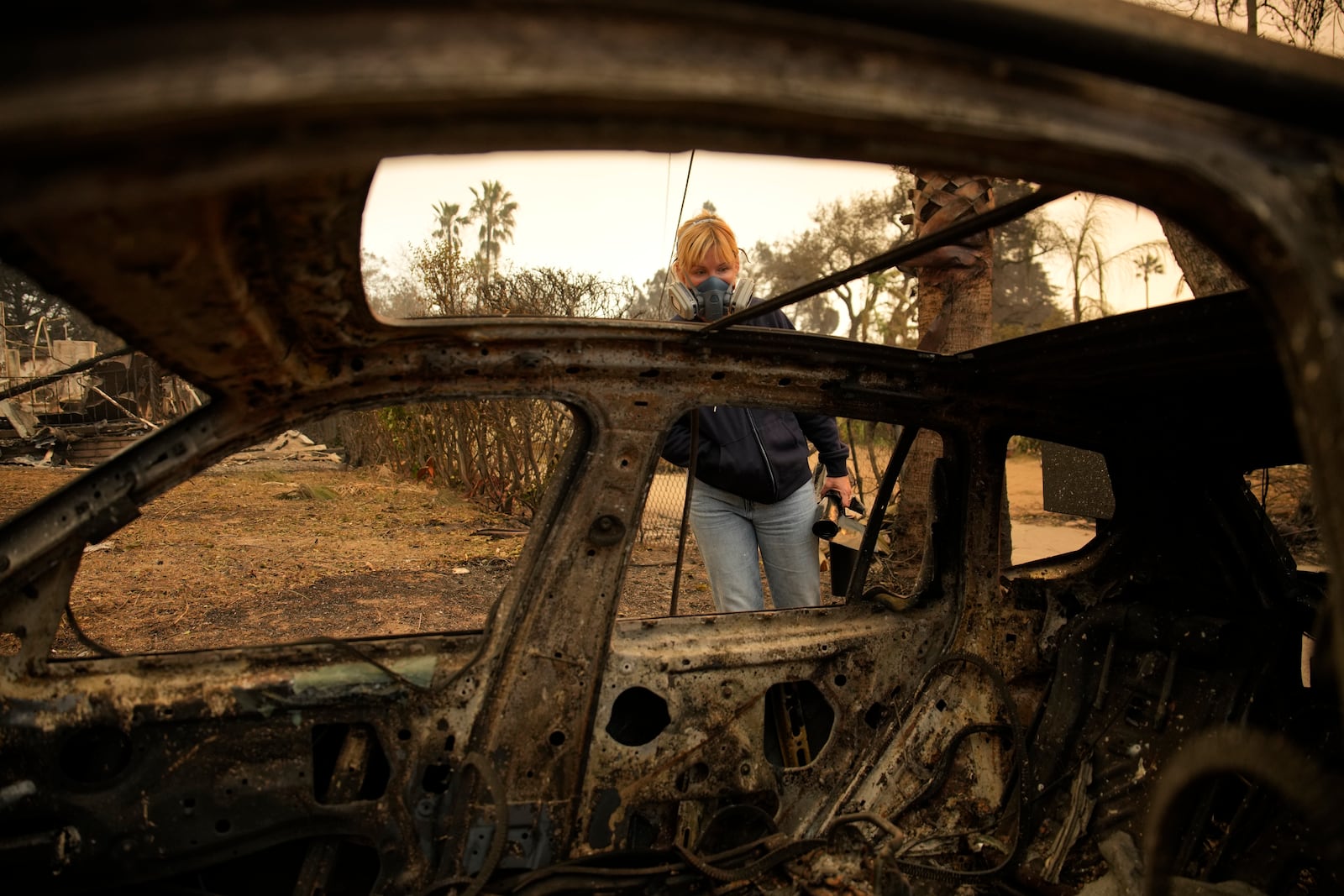 Lisa Renn looks at remains of car in Altadena, Calif., Thursday, Jan. 9, 2025. (AP Photo/John Locher)