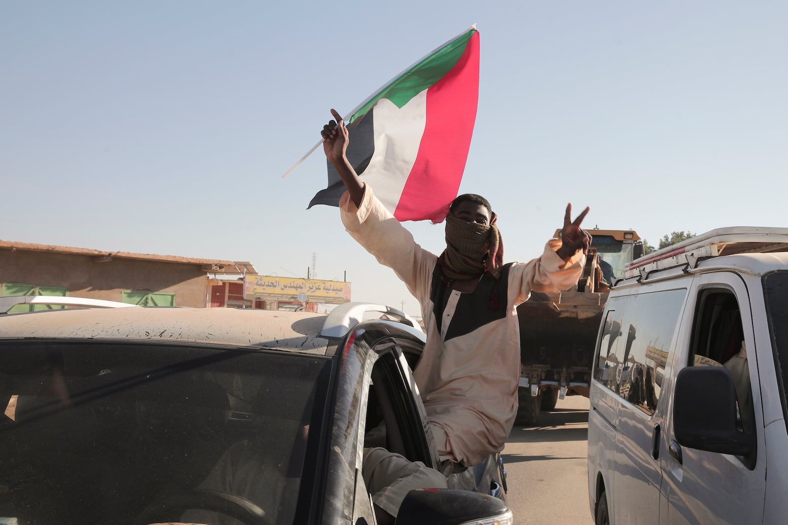 A Sudanese man gestures waving a Sudan flag following the reports that Sudan's army had entered the central city of Wad Madani and pushed out its paramilitary rivals the Rapid Support Forces (RSF), in Merowe, Sudan, Saturday, Jan.11, 2025. (AP Photo/Marwan Ali)