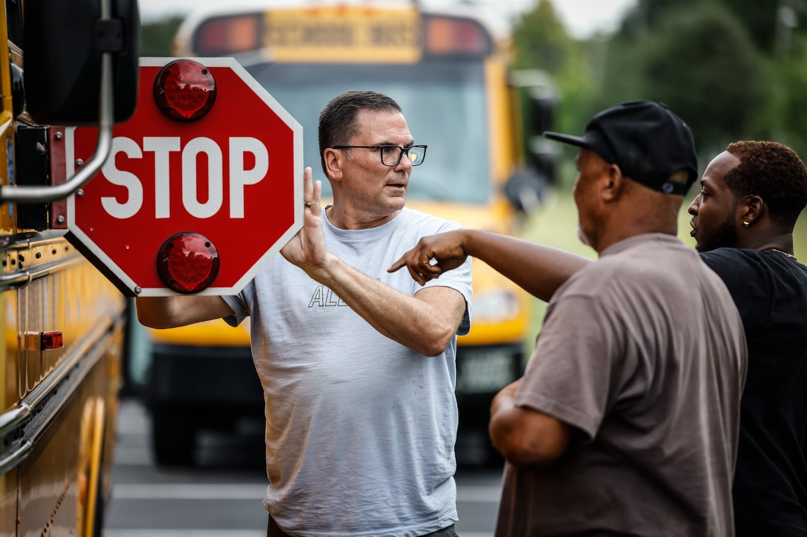 Dayton public schools bus drivers in training, from left, Tim Walden, Donald Mickler and Darell Henderson go through a check-list of a school bus while training to be drivers at Welcome Stadium Tuesday August 9, 2022. JIM NOELKER/STAFF