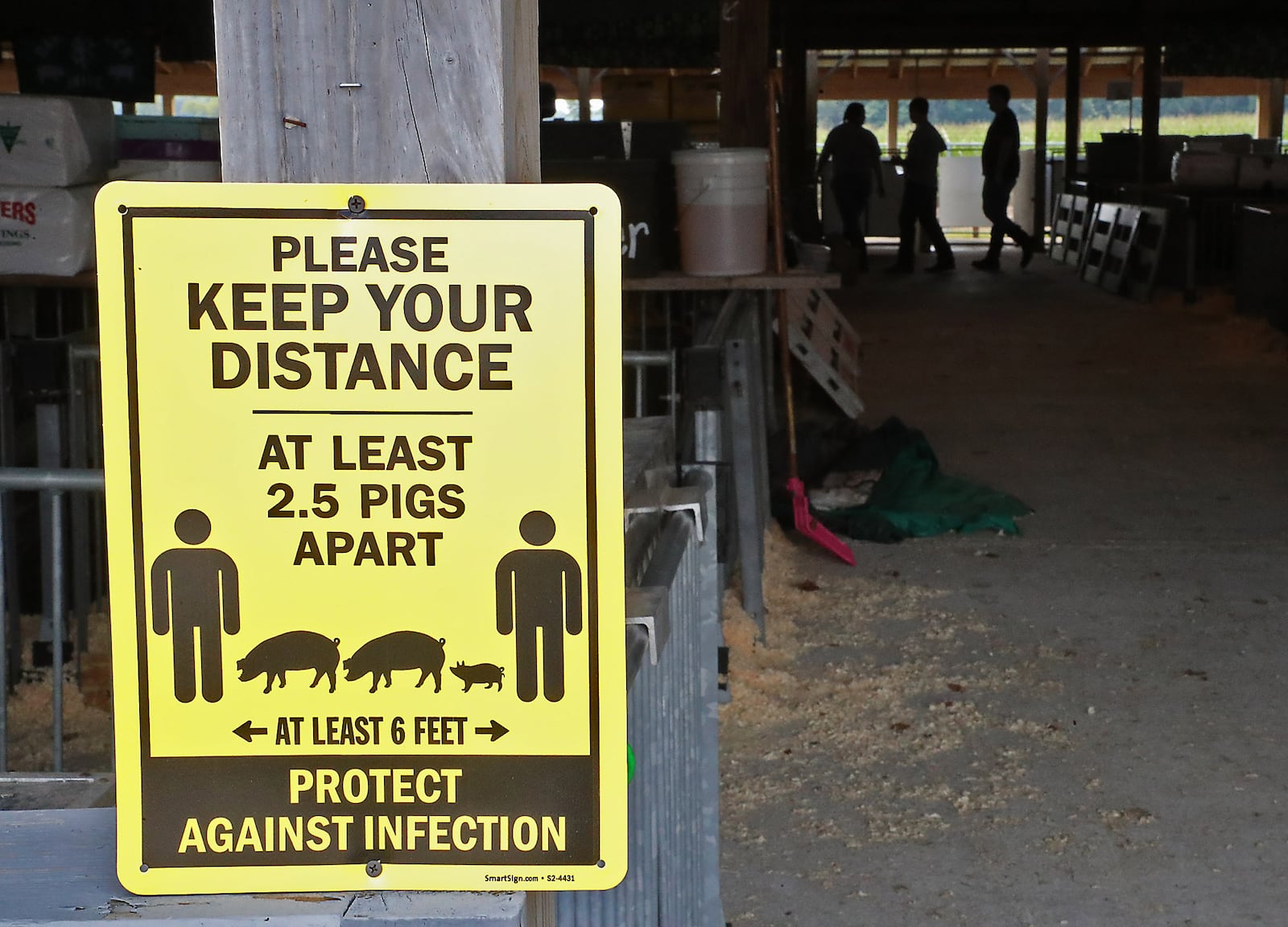 Signs on all the barns warn people about social distancing at the Champaign County Fair Thursday. BILL LACKEY/STAFF