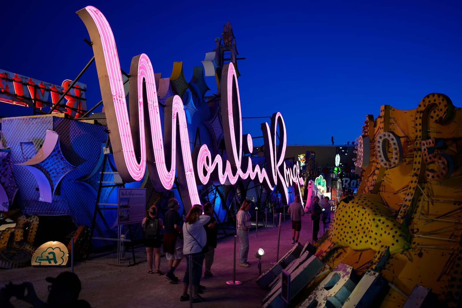 People look at signs from defunct Las Vegas casinos on display at the Neon Museum, Wednesday, April 3, 2024, in Las Vegas. (AP Photo/John Locher)