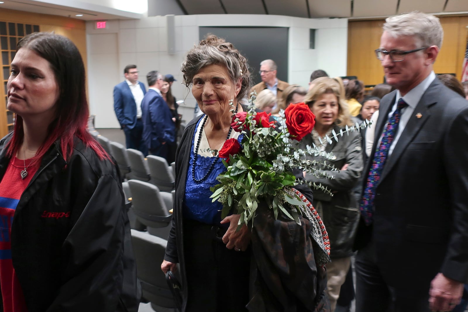 Carla Lee, a retired Wichita State University nursing professor, holds a vase of red roses to show her support for the families of victims of a deadly collision between a passenger airliner and an Army helicopter that occurred the day prior, Thursday, Jan. 30, 2025, after a prayer vigil in Wichita, Kan., where the airline passenger flight originated. (AP Photo/John Hanna)