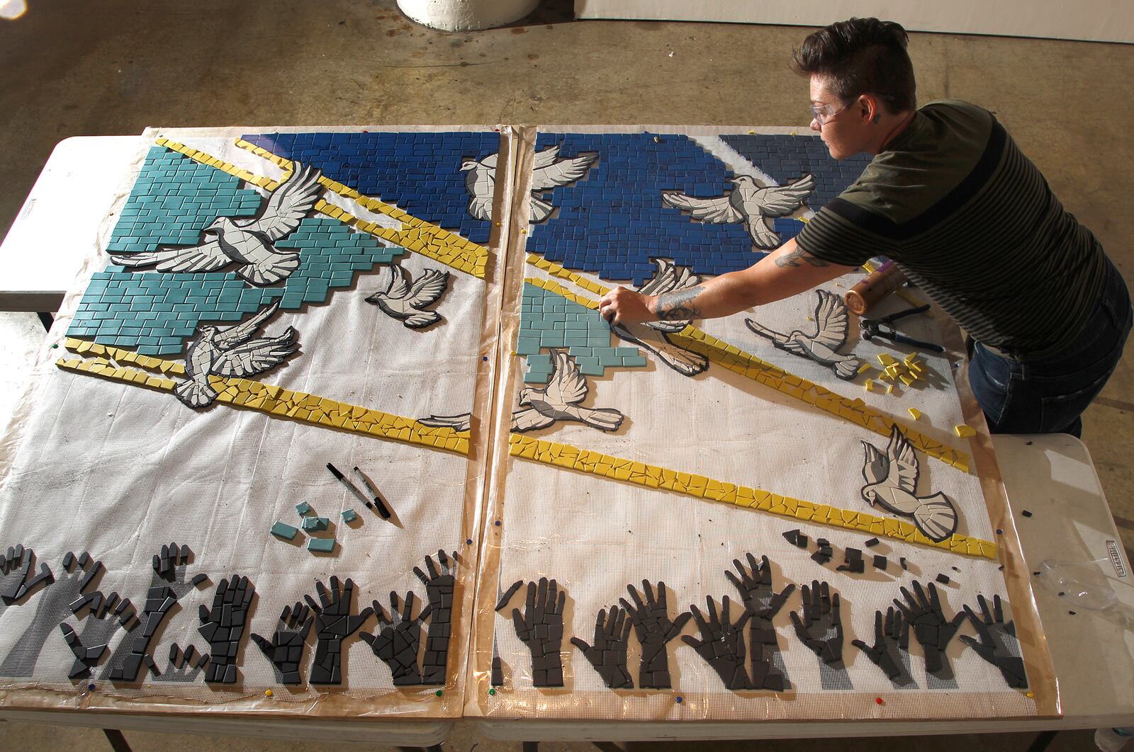 Jes McMillan, founder of The Mosaic Institute of Greater Dayton, along with her staff, designed a mosaic mural, "9 Doves," to commemorate the nine people killed in the Oregon District shooting.  LISA POWELL / STAFF