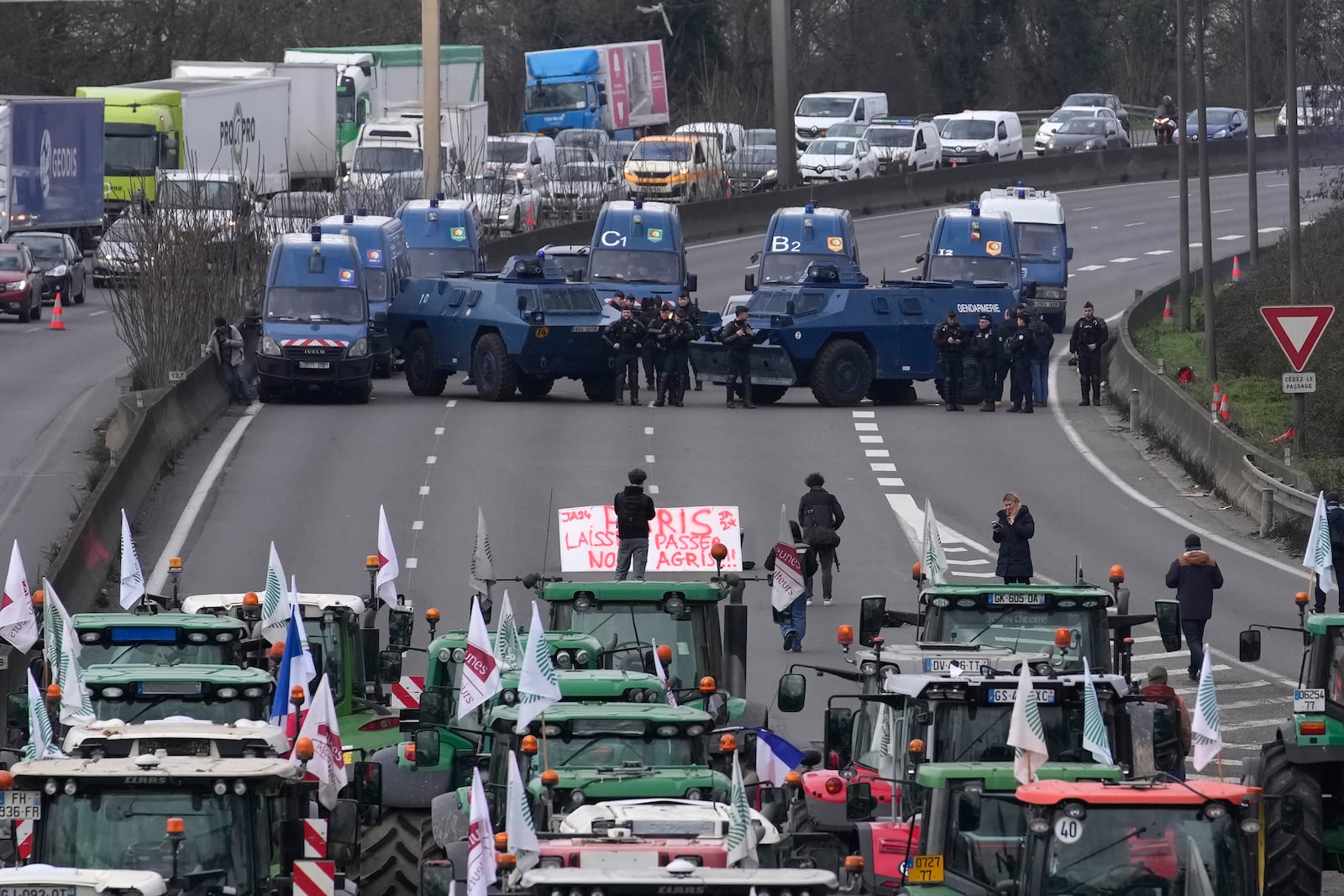 FILE- Gendarmes with armored vehicles face farmers and their tractors blocking a highway, Wednesday, Jan. 31, 2024, in Chilly-Mazarin, south of Paris. (AP Photo/Christophe Ena, File)