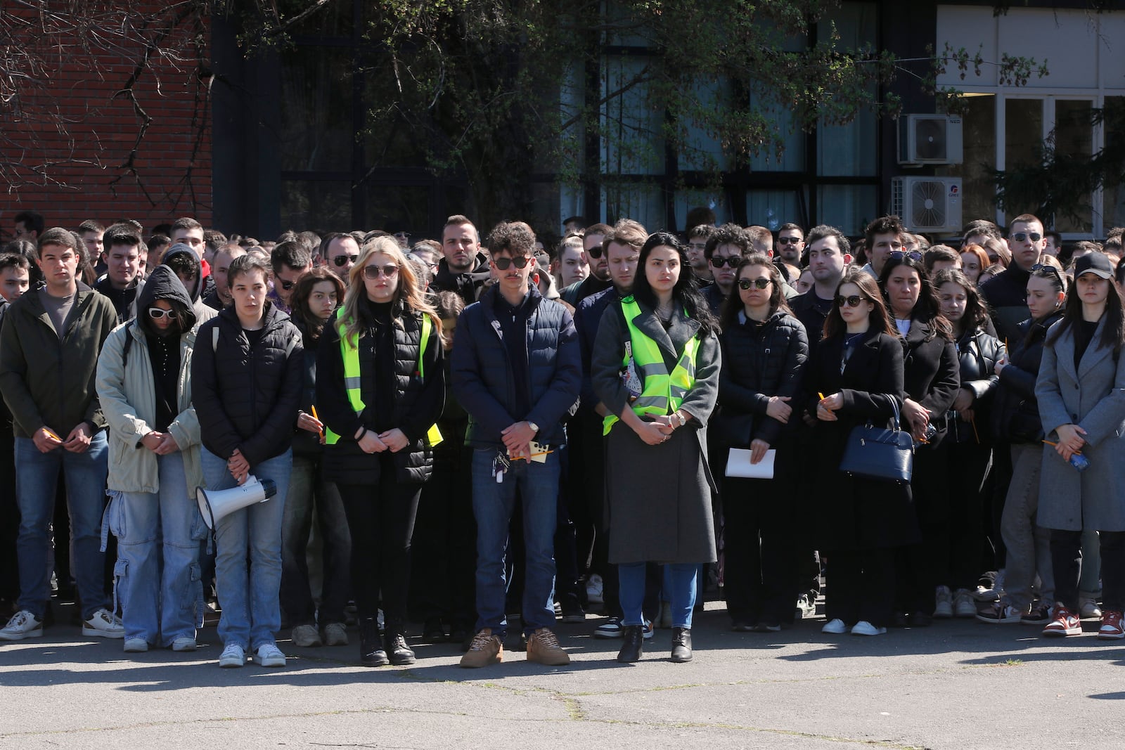 University students stand still as they mourn the victims of a massive nightclub fire in the town of Kocani, in Skopje, North Macedonia, Tuesday, March 18, 2025. (AP Photo/Boris Grdanoski)