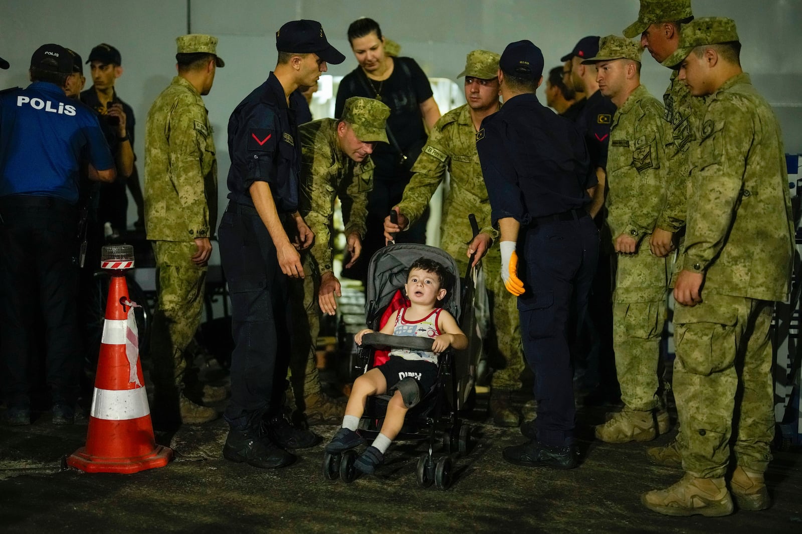 Emergency teams and military personnel help people, mostly Turkish nationals, to disembark from Turkish TCG Sancaktar military ship after being evacuated from Lebanon's capital Beirut to Turkey, in Mersin port, southern Turkey, early Friday, Oct. 11, 2024. (AP Photo/Emrah Gurel)