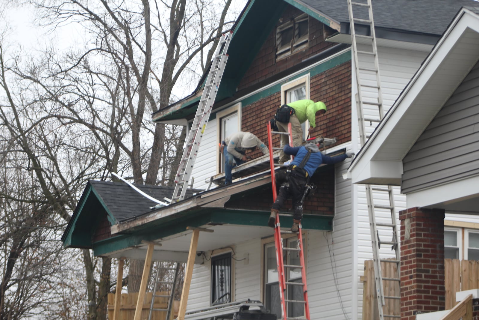 Workers make repairs to the exterior of a home in Dayton. CORNELIUS FROLIK / STAFF