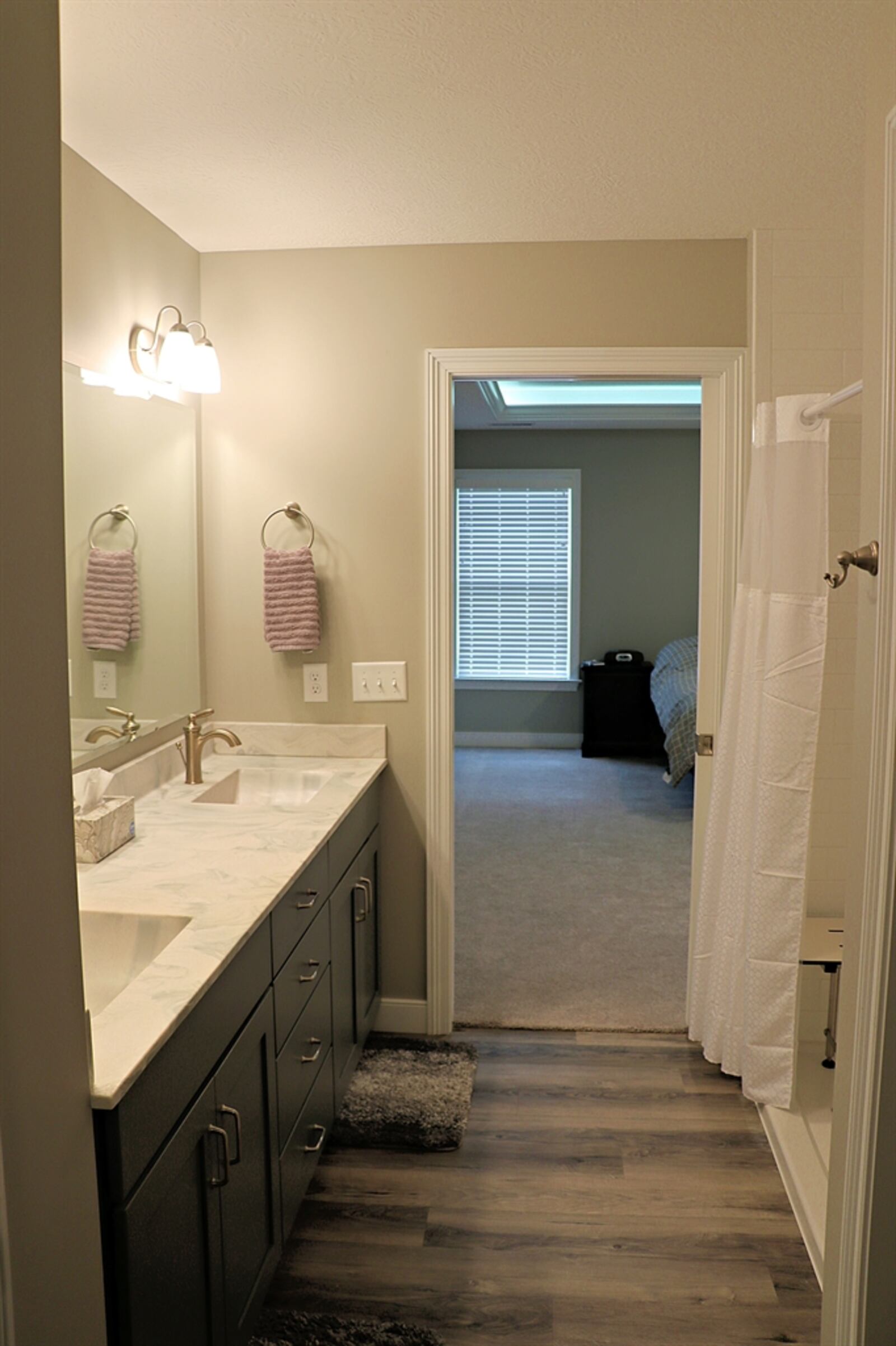 A pocket door opens into the spacious bathroom that includes an elevated double-sink vanity.