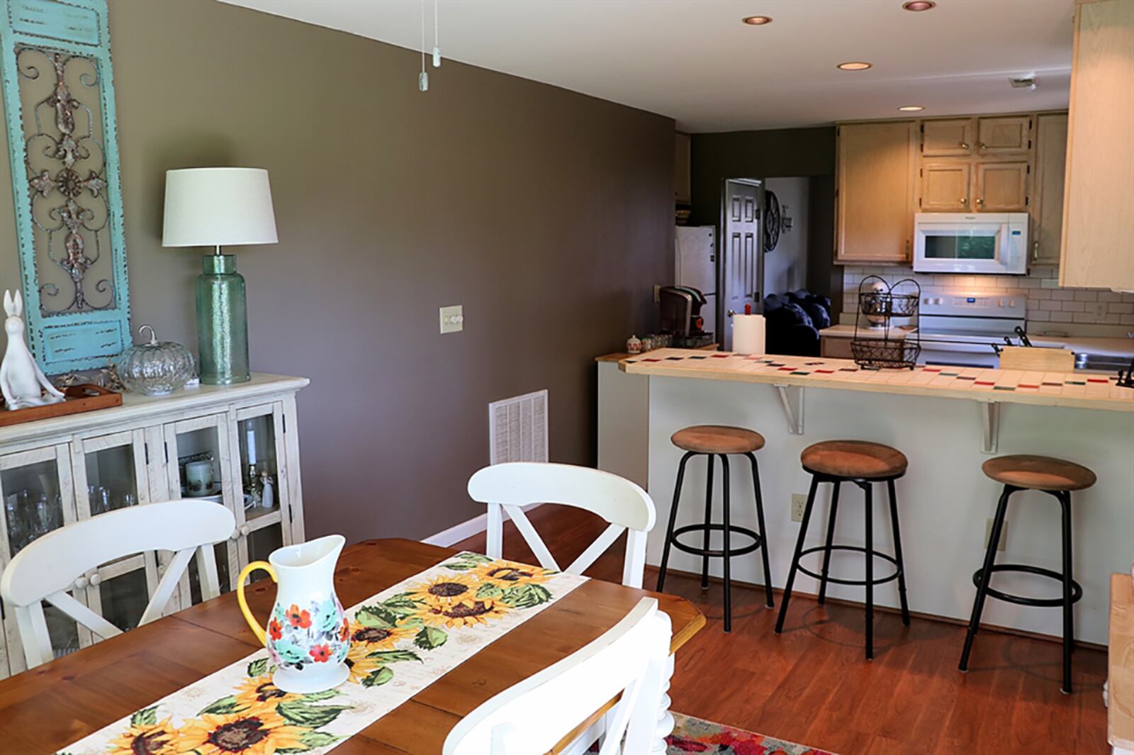 A breakfast bar extends off the peninsula counter, offering seating for up to four. The breakfast bar has a ceramic-tile countertop with colorful accents. Wood-laminate flooring fills the kitchen and continues into the adjoining dining area. CONTRIBUTED PHOTO BY KATHY TYLER