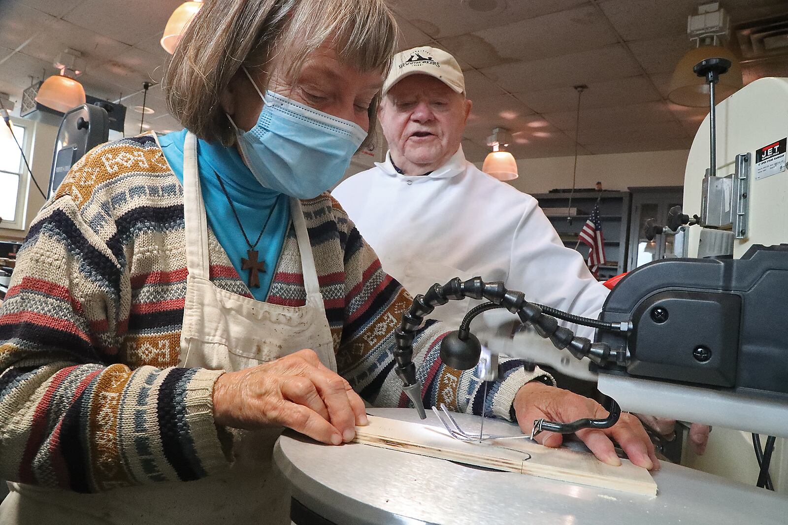 Kenneth Magill shows Carol Suddath how to operate a jig saw in the wood shop at the Ohio Masonic Home. BILL LACKEY/STAFF