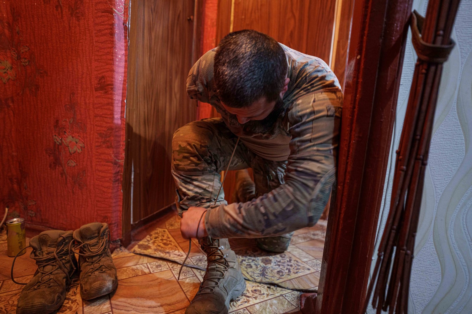 Ukrainian soldier Oleksandr Zhalinskyi of the Azov brigade, who lost his right arm in battle, ties his shoelaces in his apartment in Ukraine's Donetsk region on Jan. 31, 2025. (AP Photo/Evgeniy Maloletka)