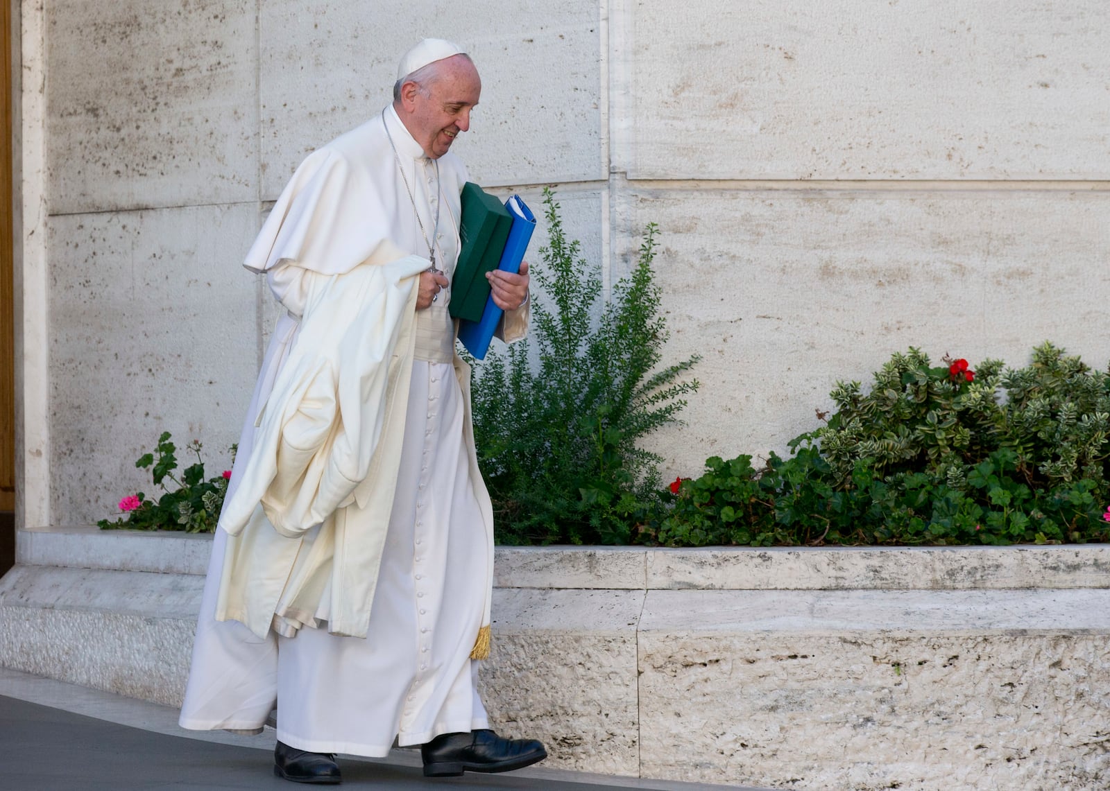 FILE - In this Oct. 24, 2015 file photo, Pope Francis carries his coat and documents as he leaves after a morning session of the last day of the Synod of bishops, at the Vatican. (AP Photo/Alessandra Tarantino, file)