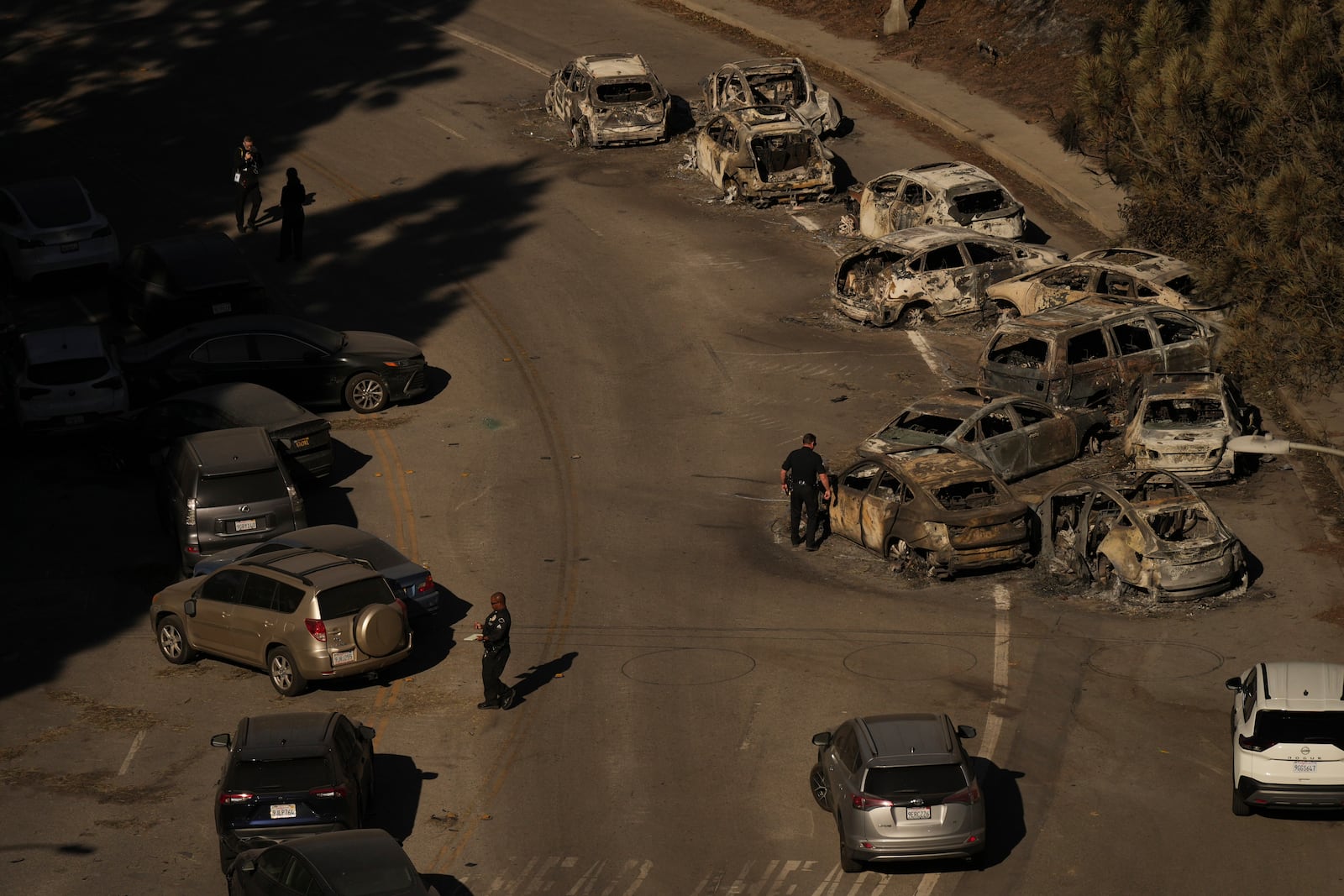 Police officers inspect cars abandoned on Sunset Boulevard during by the Palisades Fire in Palisades, Calif., Wednesday, Jan. 15, 2025. (AP Photo/Jae C. Hong)