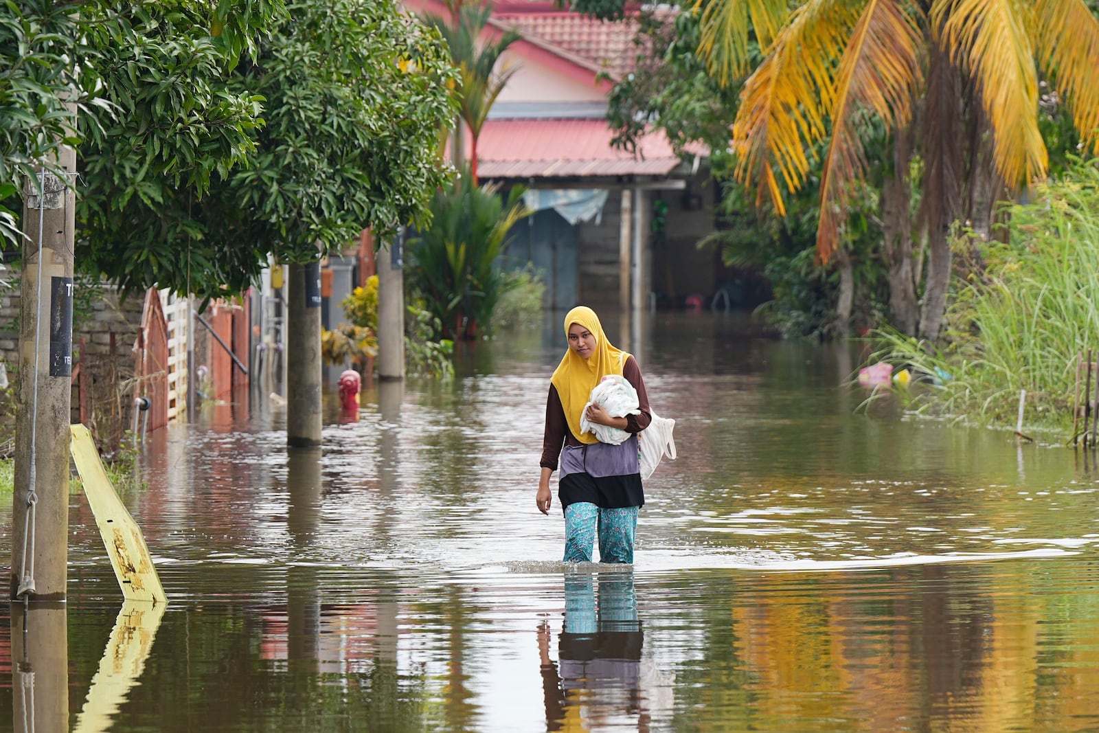 A woman wades through floodwater in Tumpat, on the outskirts of Kota Bahru in Kelantan state on the east coast of Malaysia, Tuesday, Dec. 3, 2024. (AP Photo/Vincent Thian)