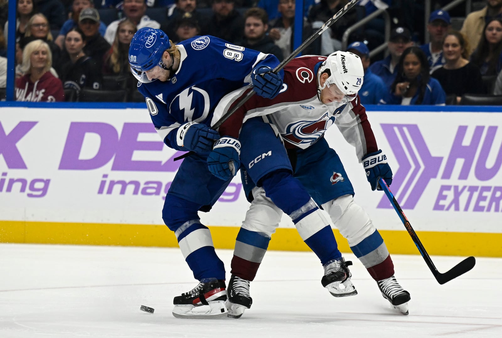 Tampa Bay Lightning defenseman J.J. Moser (90) and Colorado Avalanche center Nathan MacKinnon (29) battle for the puck during the first period of an NHL hockey game Monday, Nov. 25, 2024, in Tampa, Fla. (AP Photo/Jason Behnken)