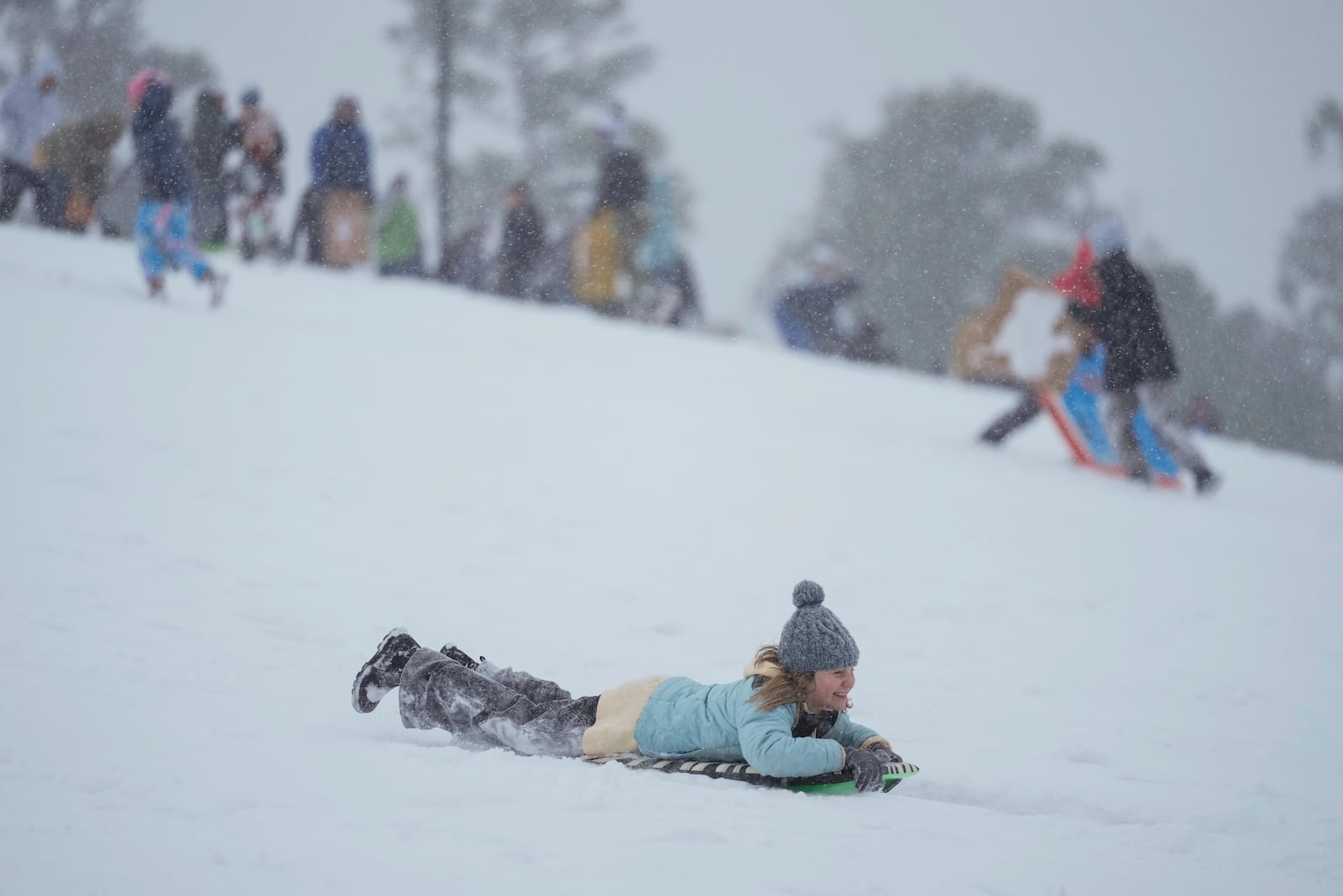 A person sleds down a hill at Herman Park Tuesday, Jan. 21, 2025, in Houston. (AP Photo/Ashley Landis)