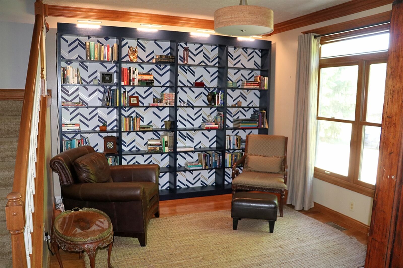 Near the spindled-accented staircase is a flexible space with a hardwood floor that is currently set up as a sitting area or library.