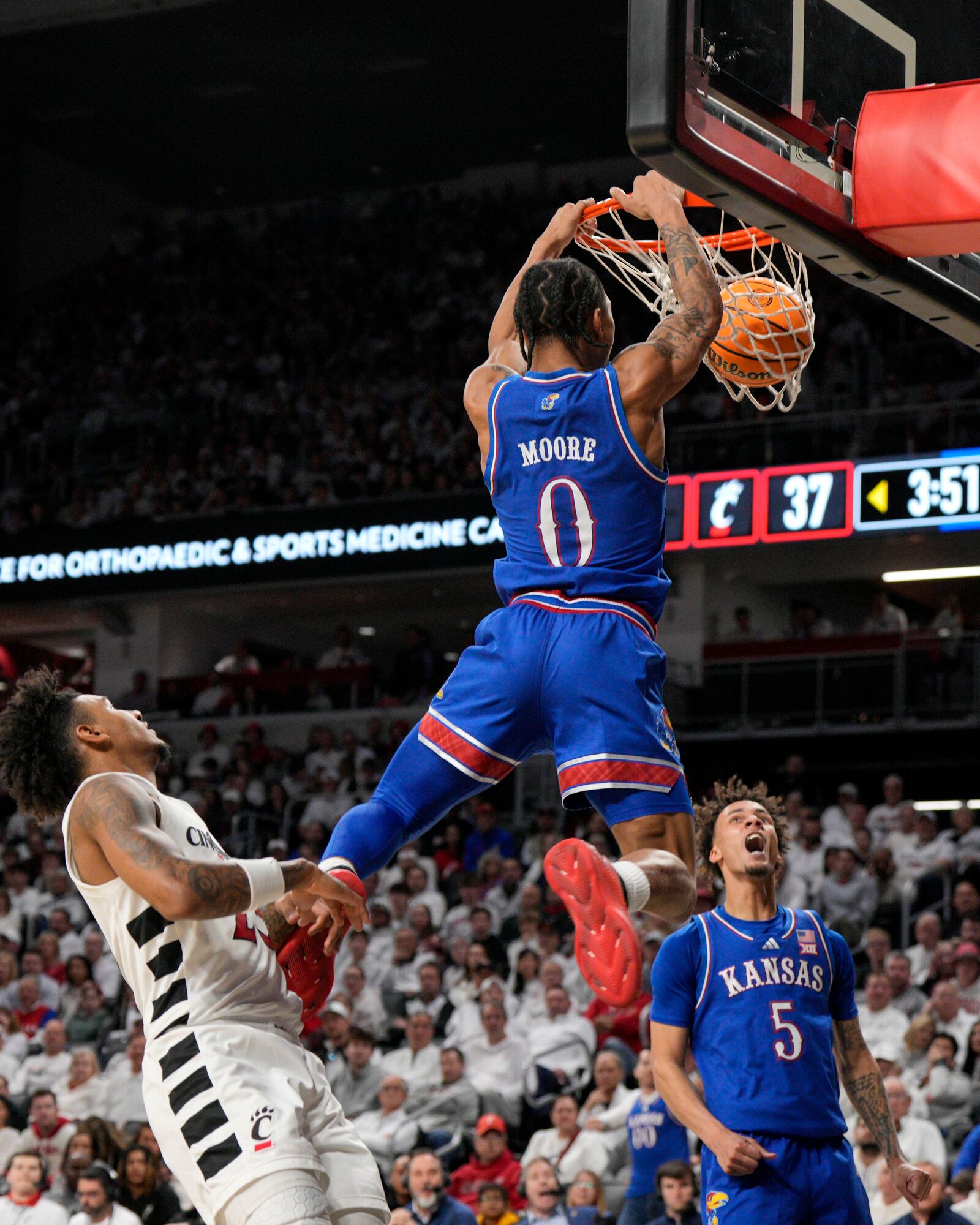 Kansas guard Shakeel Moore (0) dunks against Cincinnati forward Dillon Mitchell (23) during the second half of an NCAA college basketball game, Saturday, Jan. 11, 2025, in Cincinnati. (AP Photo/Jeff Dean)