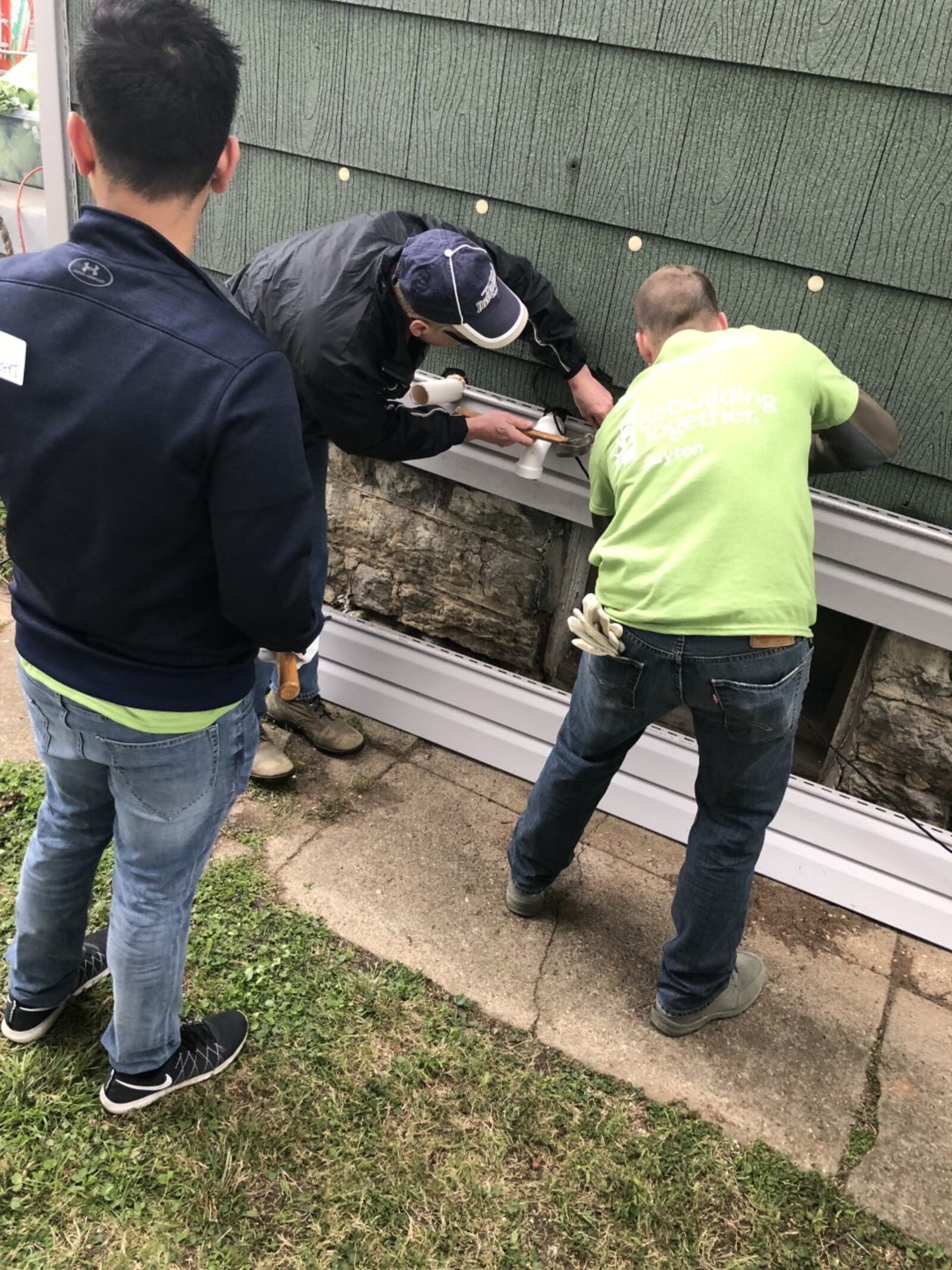 Volunteers from Booz Allen Hamilton help repair siding to a home for Rebuilding Together Dayton's 23rd annual Rebuilding Day event.