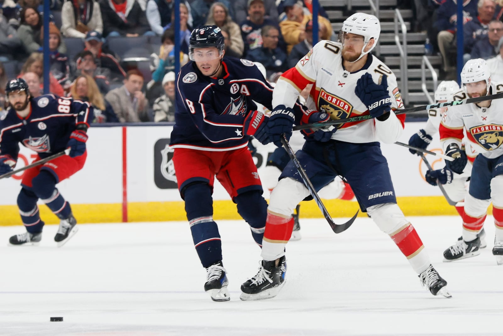 Columbus Blue Jackets' Zach Werenski, left, and Florida Panthers' A.J. Greer chase the puck during the first period of an NHL hockey game Tuesday, Oct. 15, 2024, in Columbus, Ohio. (AP Photo/Jay LaPrete)