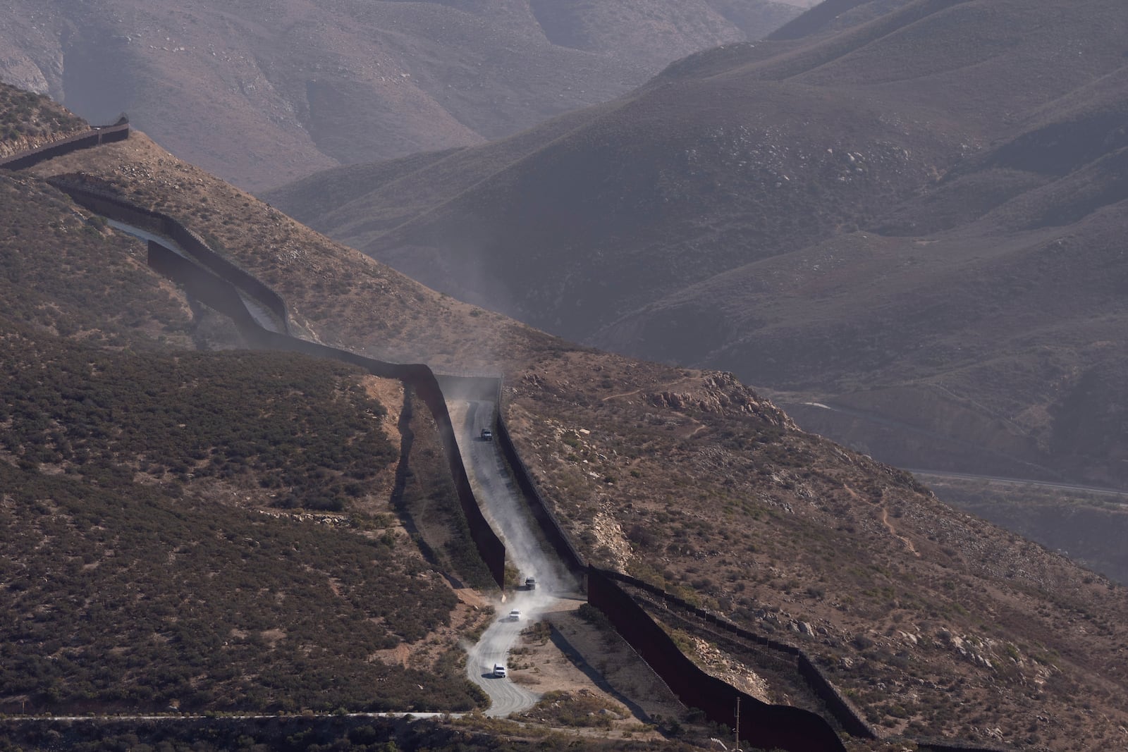 Border Patrol vehicles drive along two border walls separating Mexico from the United States Thursday, Jan. 23, 2025, in San Diego. (AP Photo/Gregory Bull)