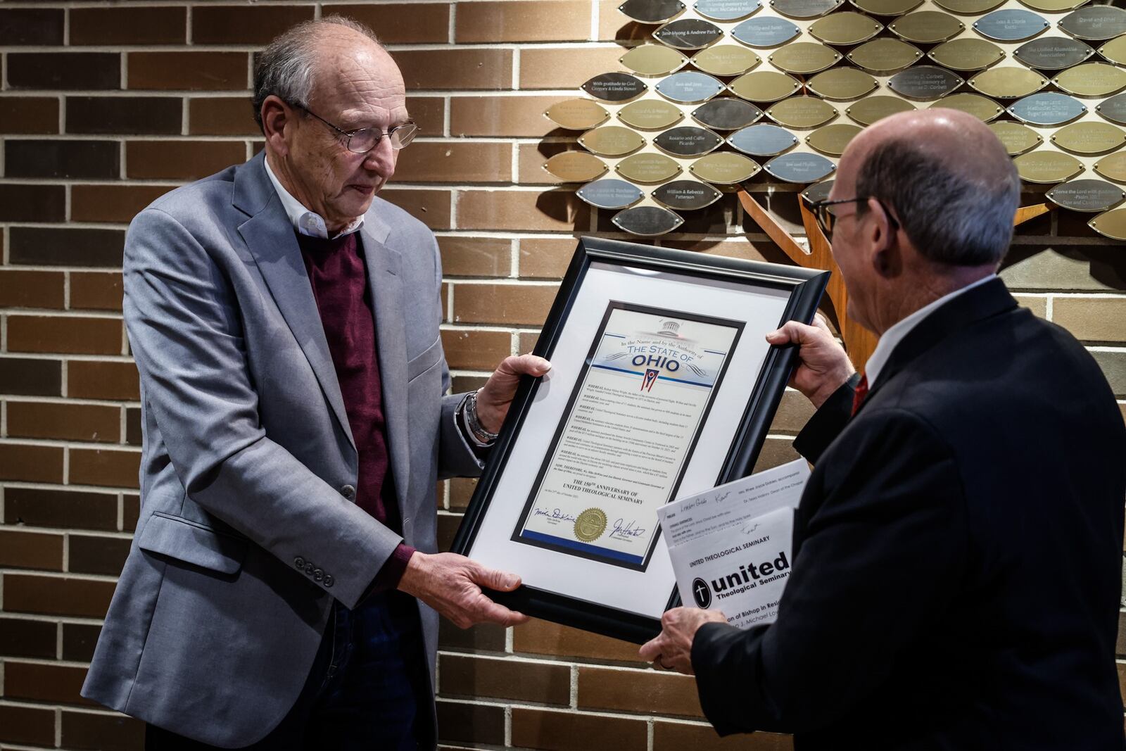 United Theological Seminary trustee, Dr. Tom Lasley, left, and seminary president Dr. Kent Millard hold a proclamation from Ohio Governor Mike DeWine and Lieutenant Governor Jon Husted celebrating the school's 150 year anniversary year. JIM NOELKER/STAFF