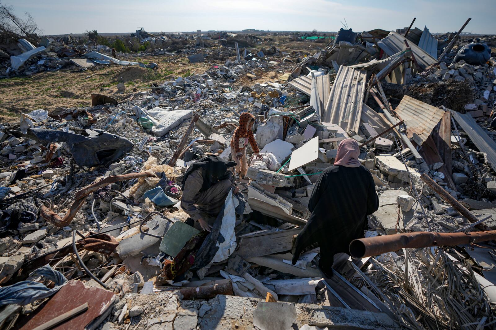 Azhar Abu Sheiban, center, and her family members salvage what they can of their belongings from the rubble of their destroyed home, days after the ceasefire deal between Israel and Hamas, in Rafah, southern Gaza Strip, Tuesday, Jan. 21, 2025. (AP Photo/Abdel Kareem Hana)