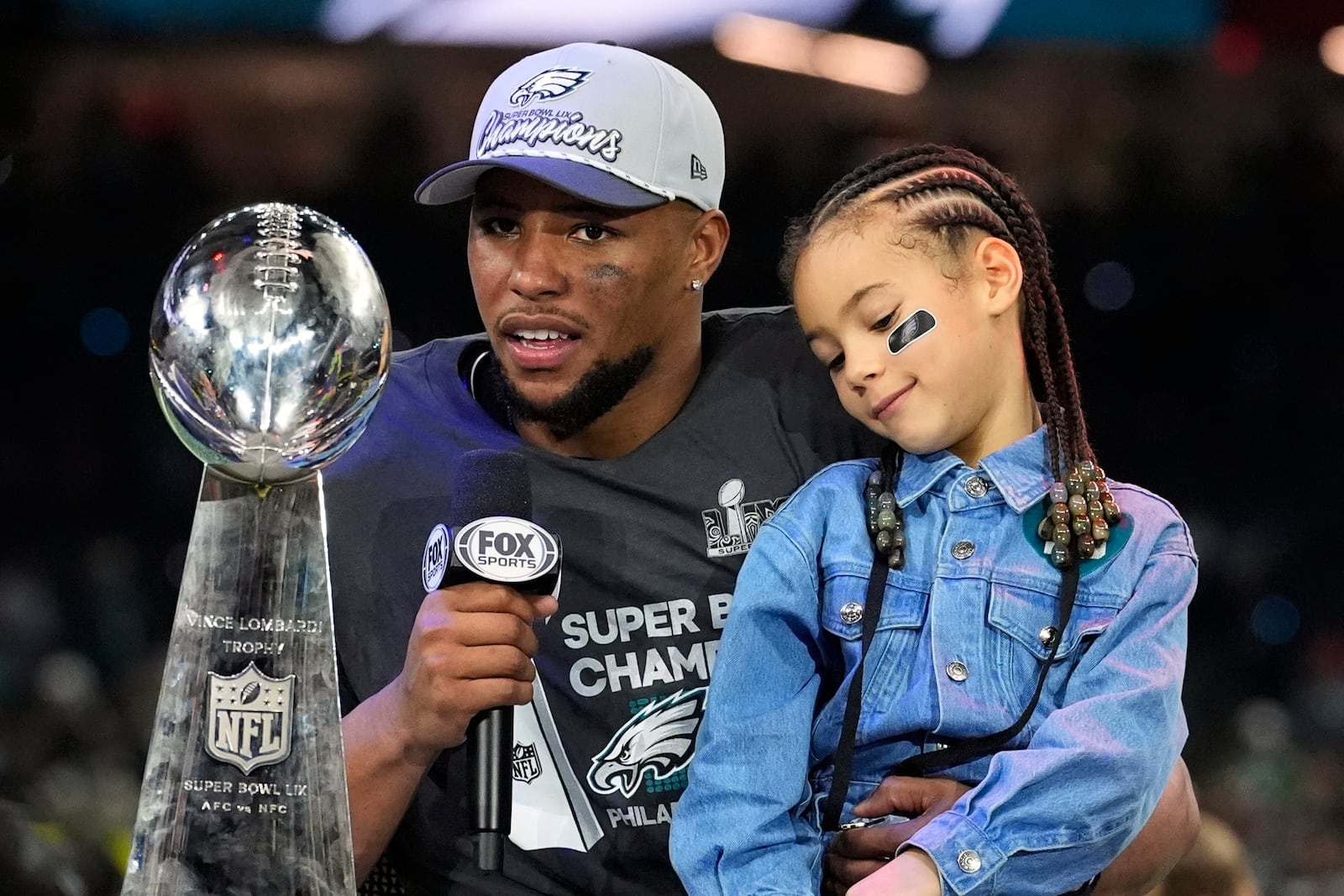 Philadelphia Eagles running back Saquon Barkley holds his daughter Jada while being interviewed after the NFL Super Bowl 59 football game against the Kansas City Chiefs, Sunday, Feb. 9, 2025, in New Orleans. (AP Photo/Brynn Anderson)