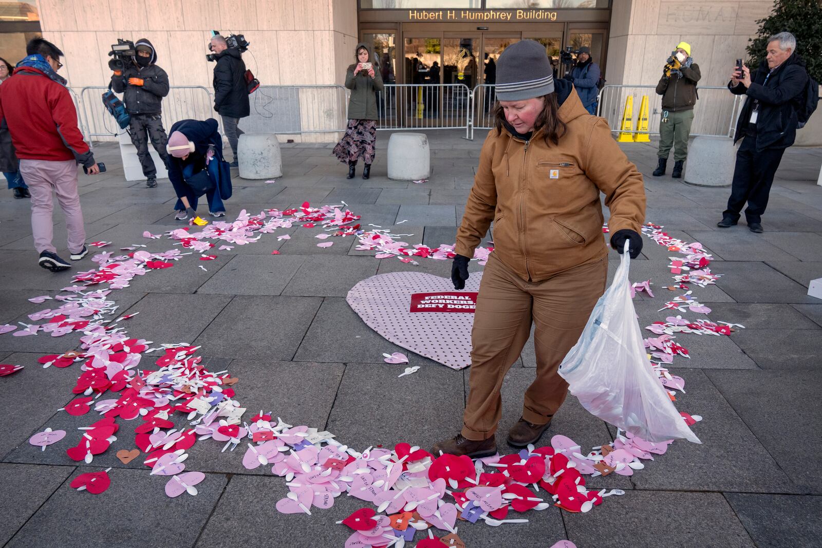 Demonstrators rallying in support of federal workers spread Valentine's Day themed messages for them outside of the Department of Health and Human Services, Friday, Feb. 14, 2025, in Washington. (AP Photo/Mark Schiefelbein)