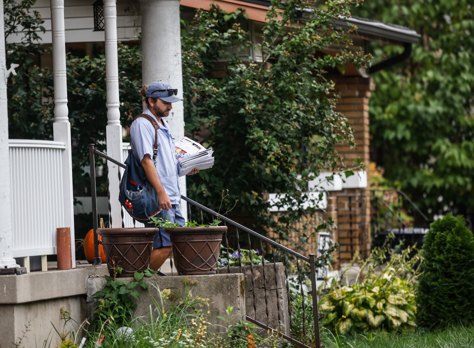 A mail carrier delivers mail on Watervliet Ave. Monday Oct. 4, 2021.  The mail may soon cost more and take long to arrive under postmasters 10-year plan. JIM NOELKER/STAFF