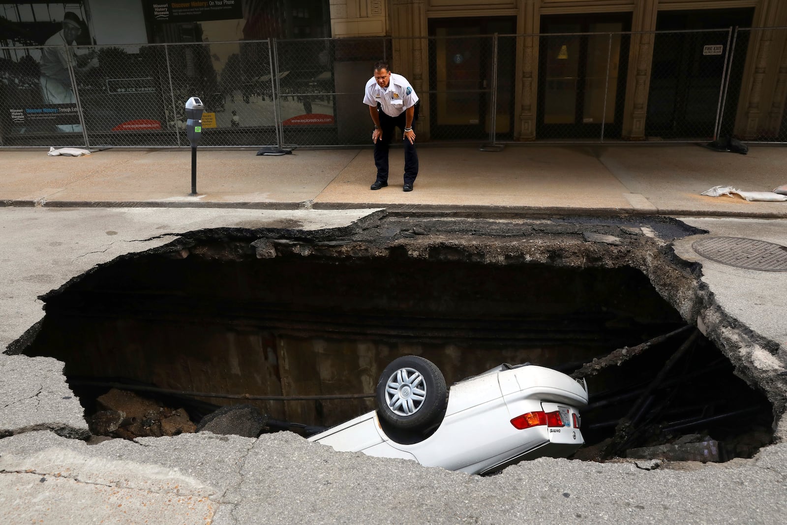 FILE - A St. Louis police officer looks over a large hole in 6th Street, Thursday, June 29, 2017, in St. Louis, that swallowed a Toyota Camry between Olive and Locust Streets. (Christian Gooden/St. Louis Post-Dispatch via AP, File)