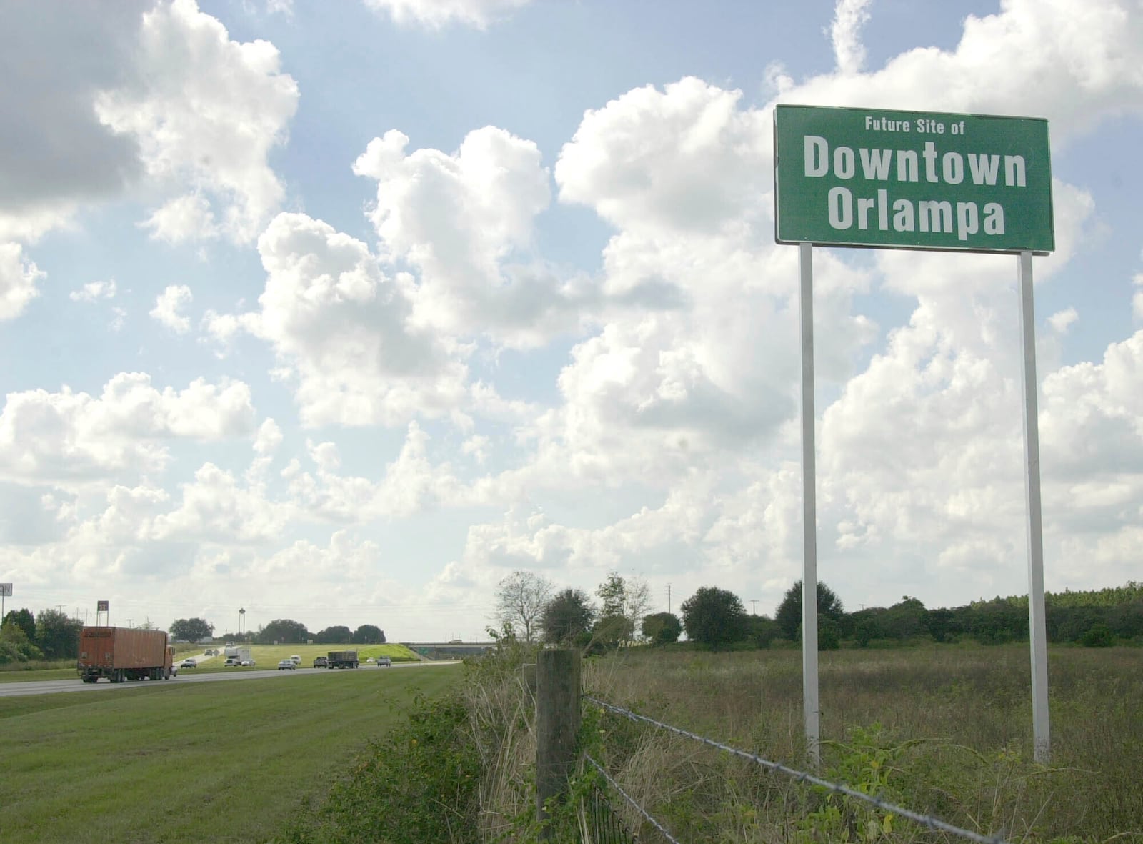 FILE - A tongue-in-cheek sign referencing what someday might be the heart of the sprawling metro areas of Orlando and Tampa is seen, installed by a private landowner, along Interstate 4 in Polk City, Fla., Oct. 24, 2002. (AP Photo/Peter Cosgrove, File)