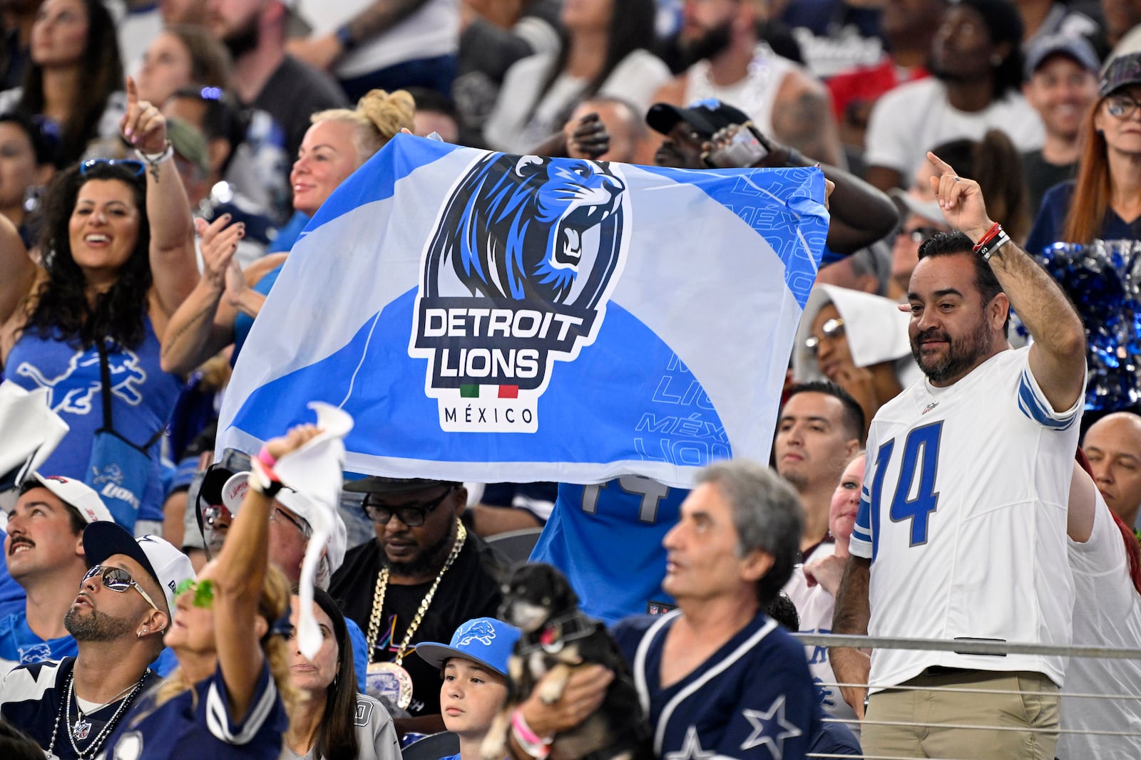 Fans hold up a Detroit Lions team flag that has a Mexico national flag colors on it in the second half of an NFL football game against the Dallas Cowboys in Arlington, Texas, Sunday, Oct. 13, 2024. (AP Photo/Jerome Miron)