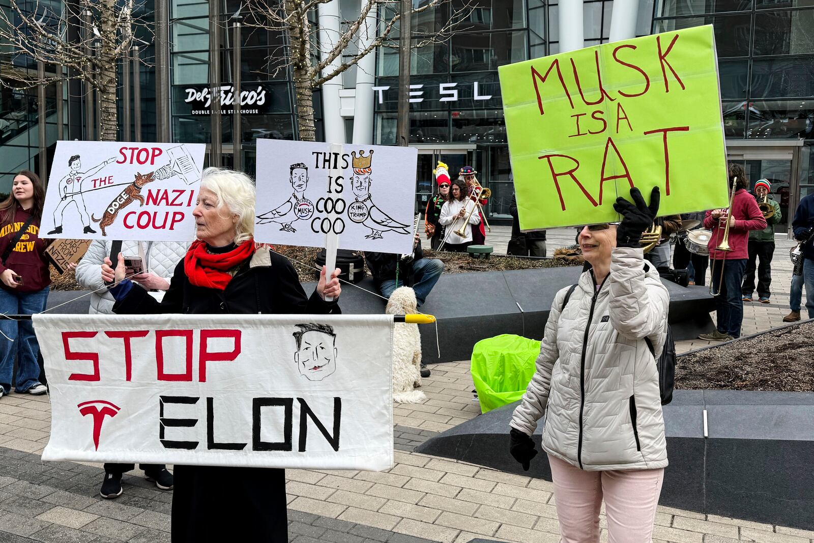 FILE - Protesters rally outside of a Tesla store in Boston, Saturday, March 1, 2025, against the company's CEO, Elon Musk, who is leading an effort to cut government jobs on behalf of President Donald Trump. (AP Photo/Rodrique Ngowi, File)