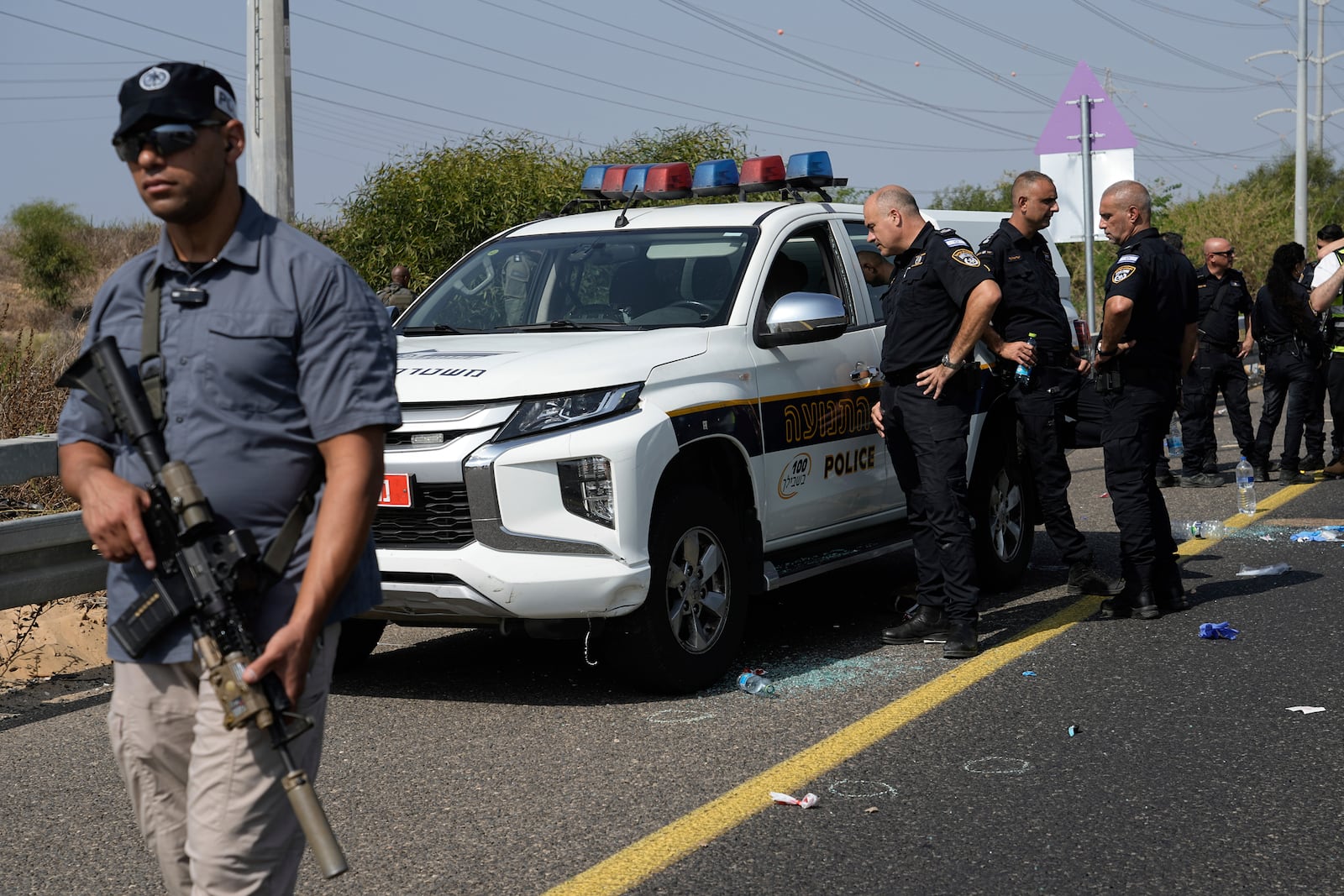 Israeli security forces examine the scene of a shooting attack where they said a police officer was killed and several others were wounded near Yavne, Israel, Tuesday, Oct. 15, 2024. (AP Photo/Tsafrir Abayov)