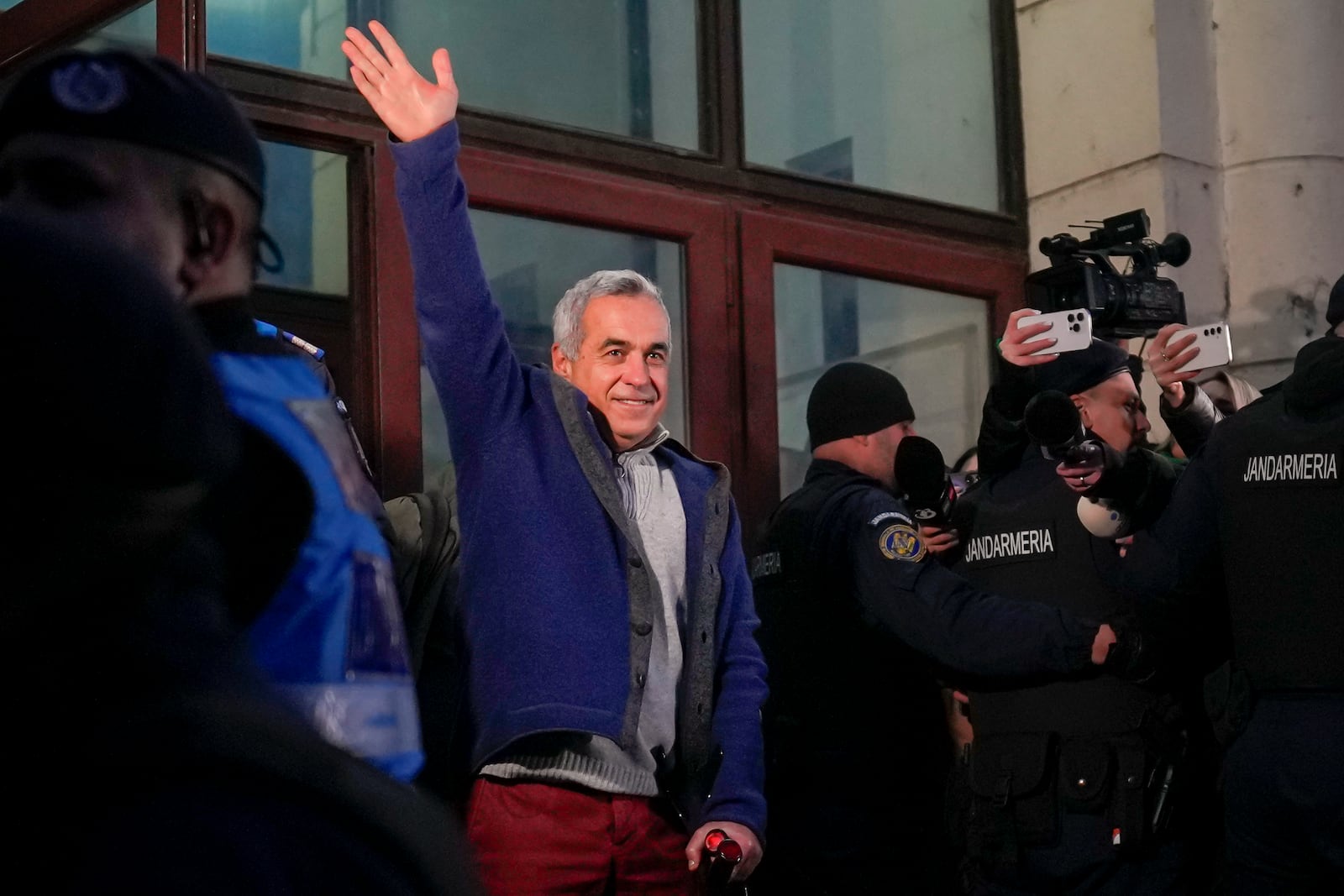 Calin Georgescu, the winner of Romania's first round of presidential election, annulled by the Constitutional Court, waves to supporters as he leaves the General Prosecutor's Office, after being stopped in traffic and taken in for questioning in Bucharest, Romania, Wednesday, Feb. 26, 2025. (AP Photo/Vadim Ghirda)