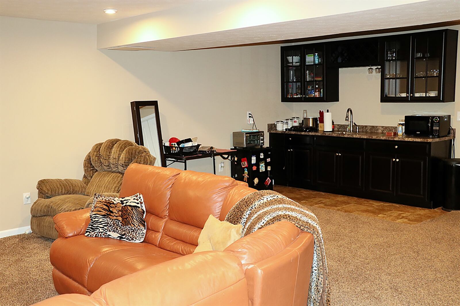 The center of the basement is a recreation room with a wall of cabinetry and countertop. The wet bar area as a sink, granite countertop, glass-panel hanging cabinets with glass and bottle racks and under-counter appliance nooks. CONTRIBUTED PHOTO BY KATHY TYLER